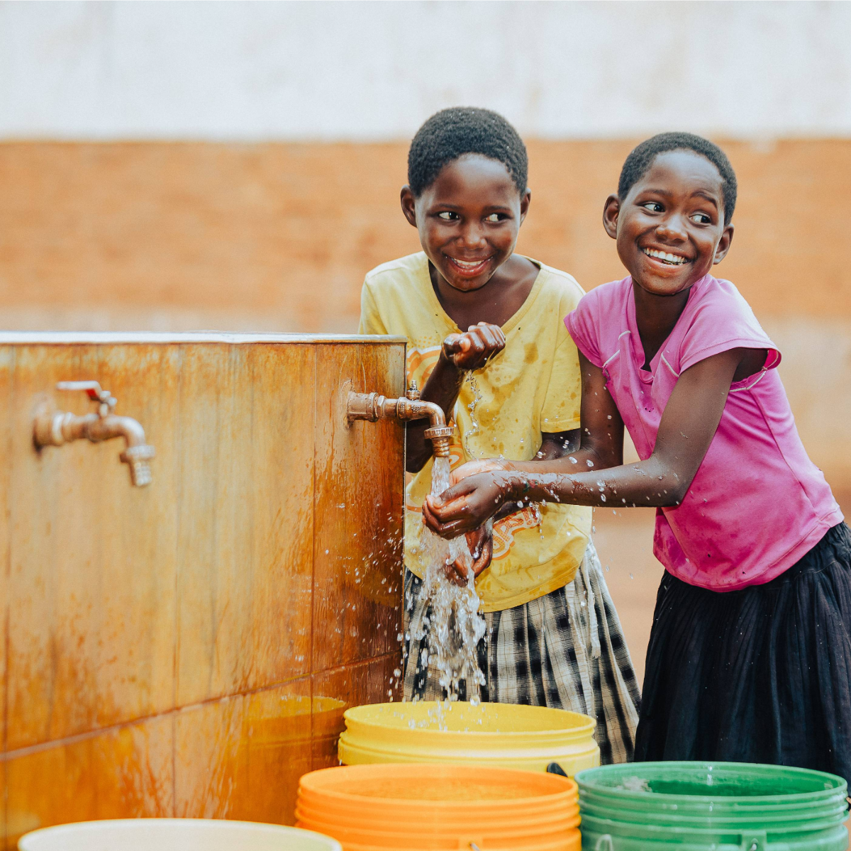 Two young girls in Malawi with a new mechanised tap installed near their home