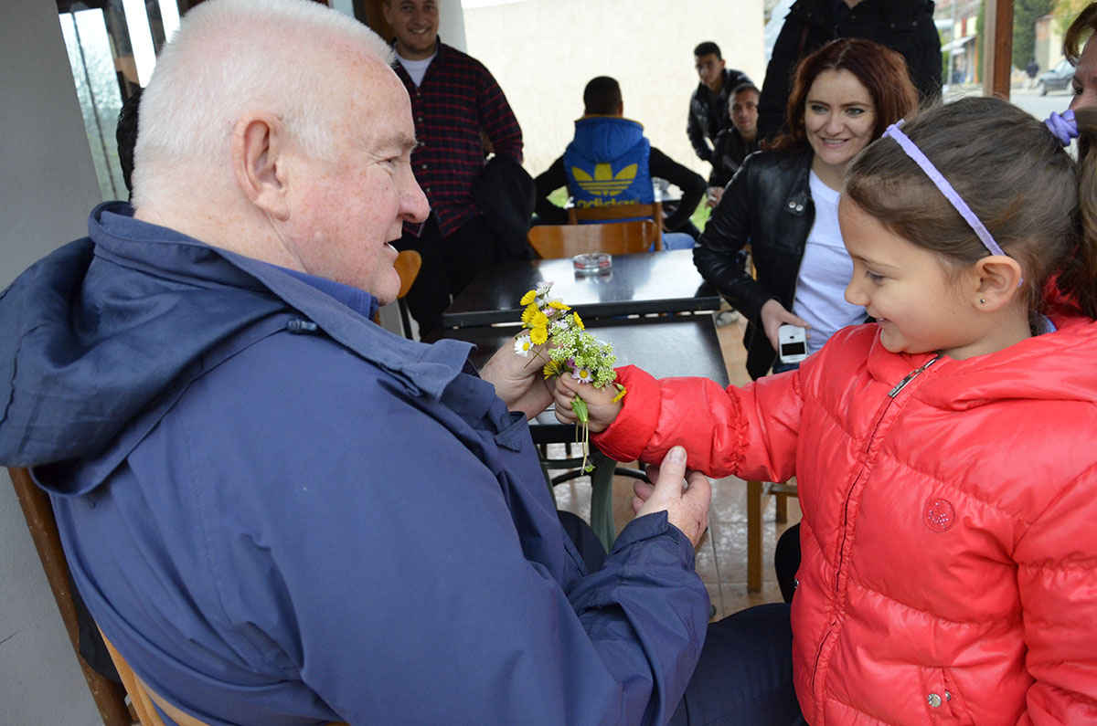 Child holds out some flowers to a man in Albania