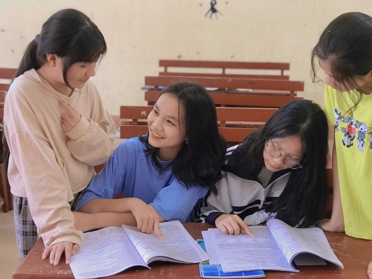 Vienamese girls gathered around a desk to study together at school