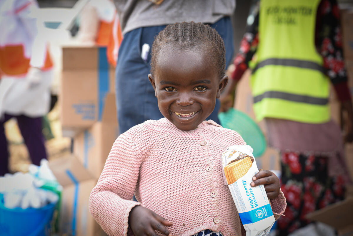 Four-year-old internally displaced girl from the DRC holding food and smiling