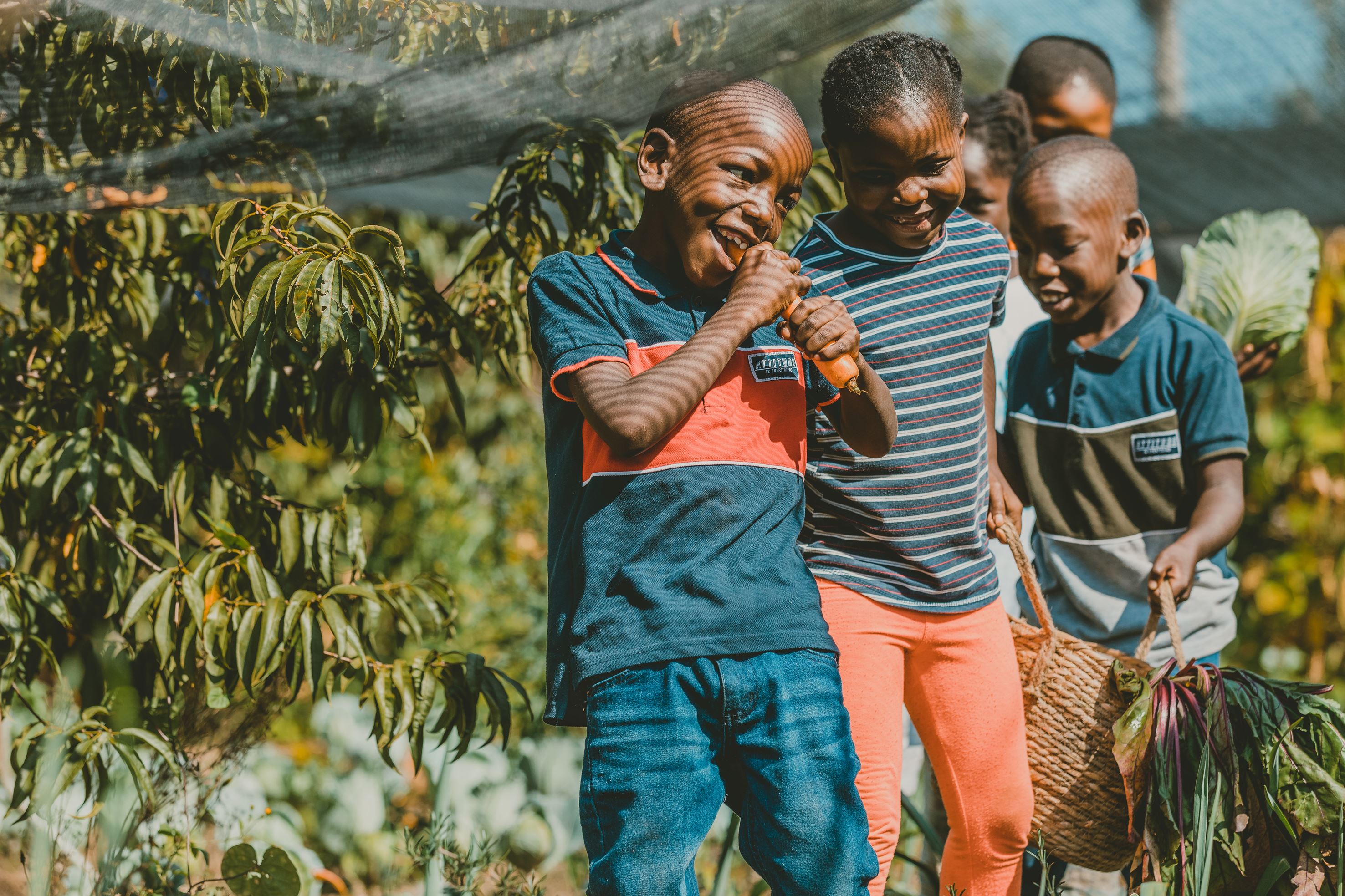 Three children smiling to each other in front a farm
