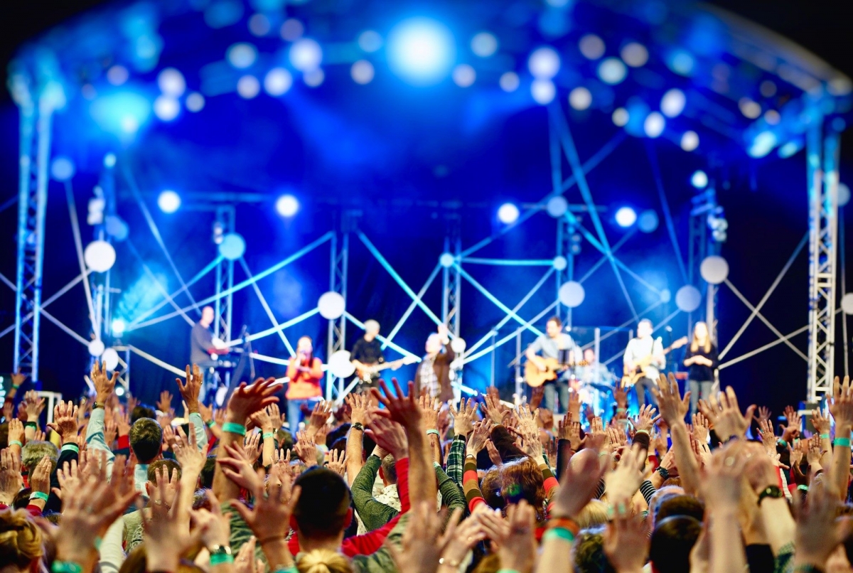 Stage with musicians, blue lights and the back of a crowd