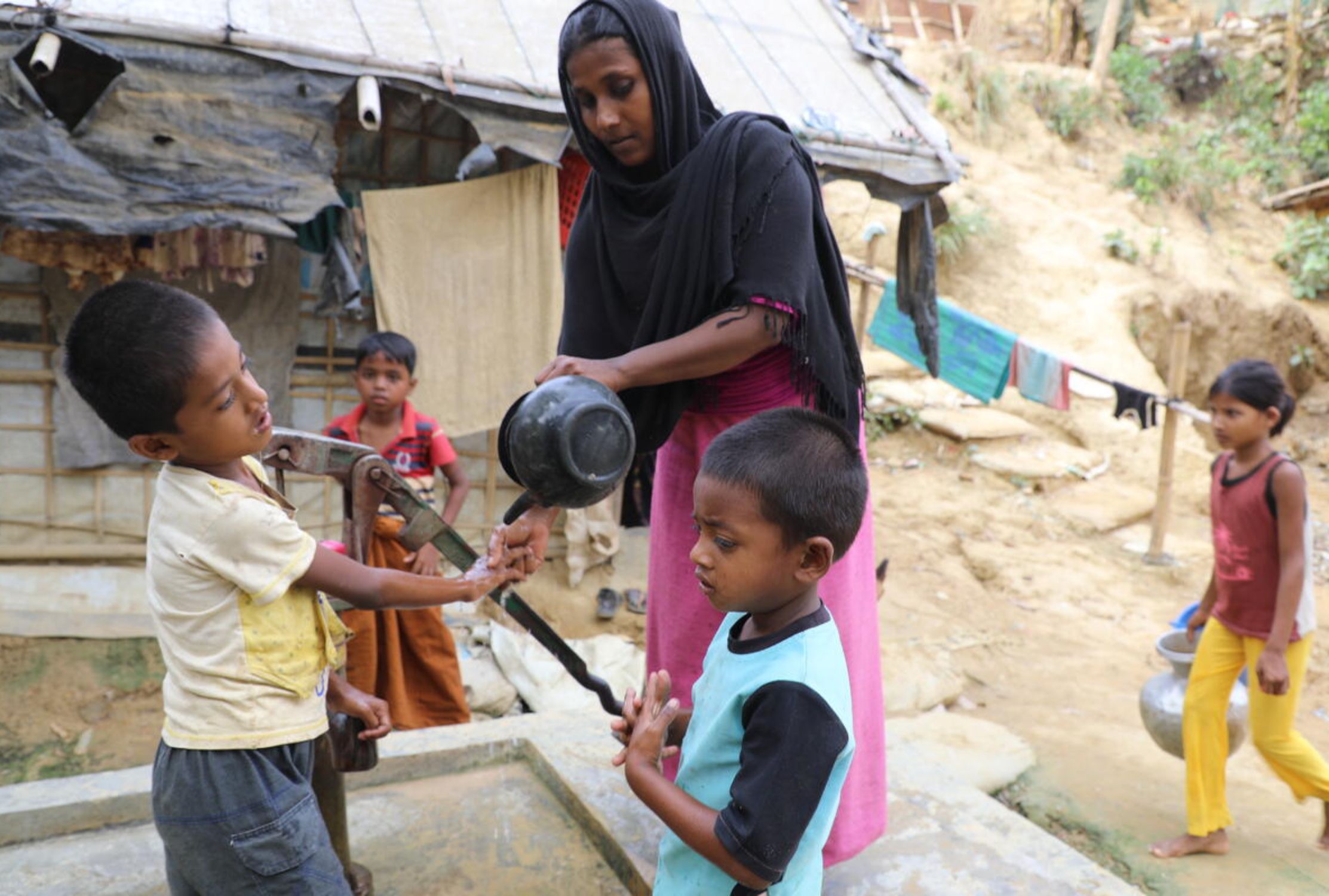 Mother from Bangladesh washing her two boys' hands