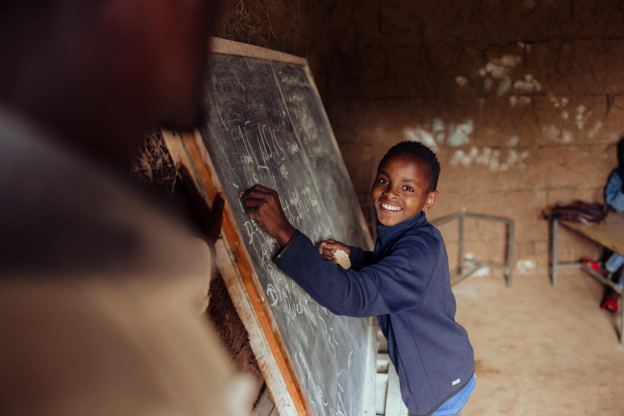 A boy from Ethiopia writing on a blackboard in a classroom