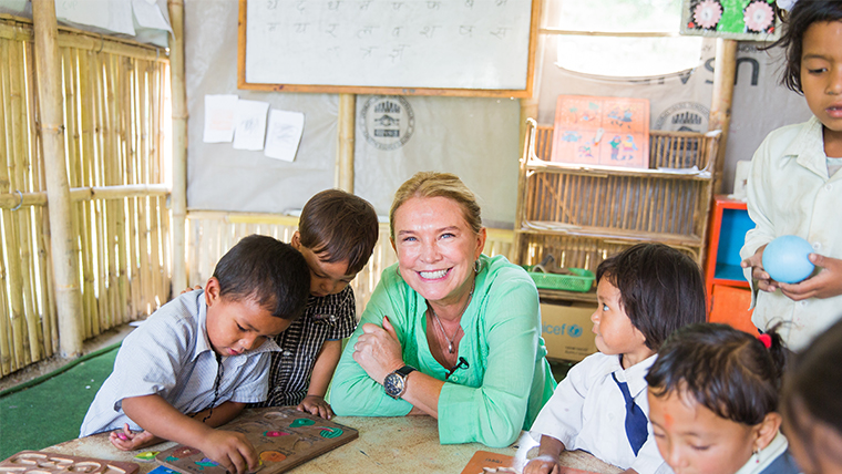 Amanda Redman smiles surrounded by playing children in Nepal 