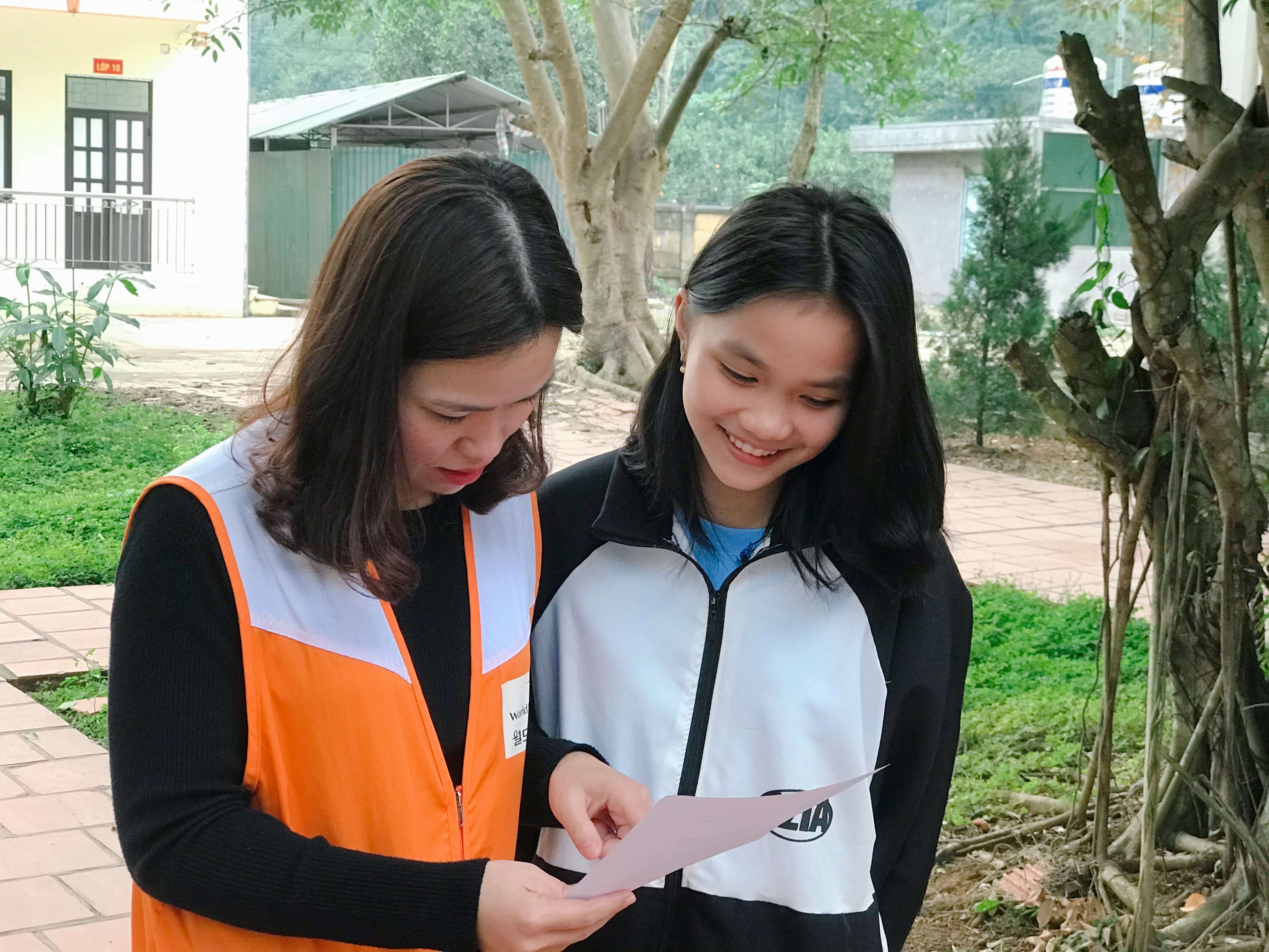 Vietnamese teenage girl standing next to a World Vision Vietnam staff member