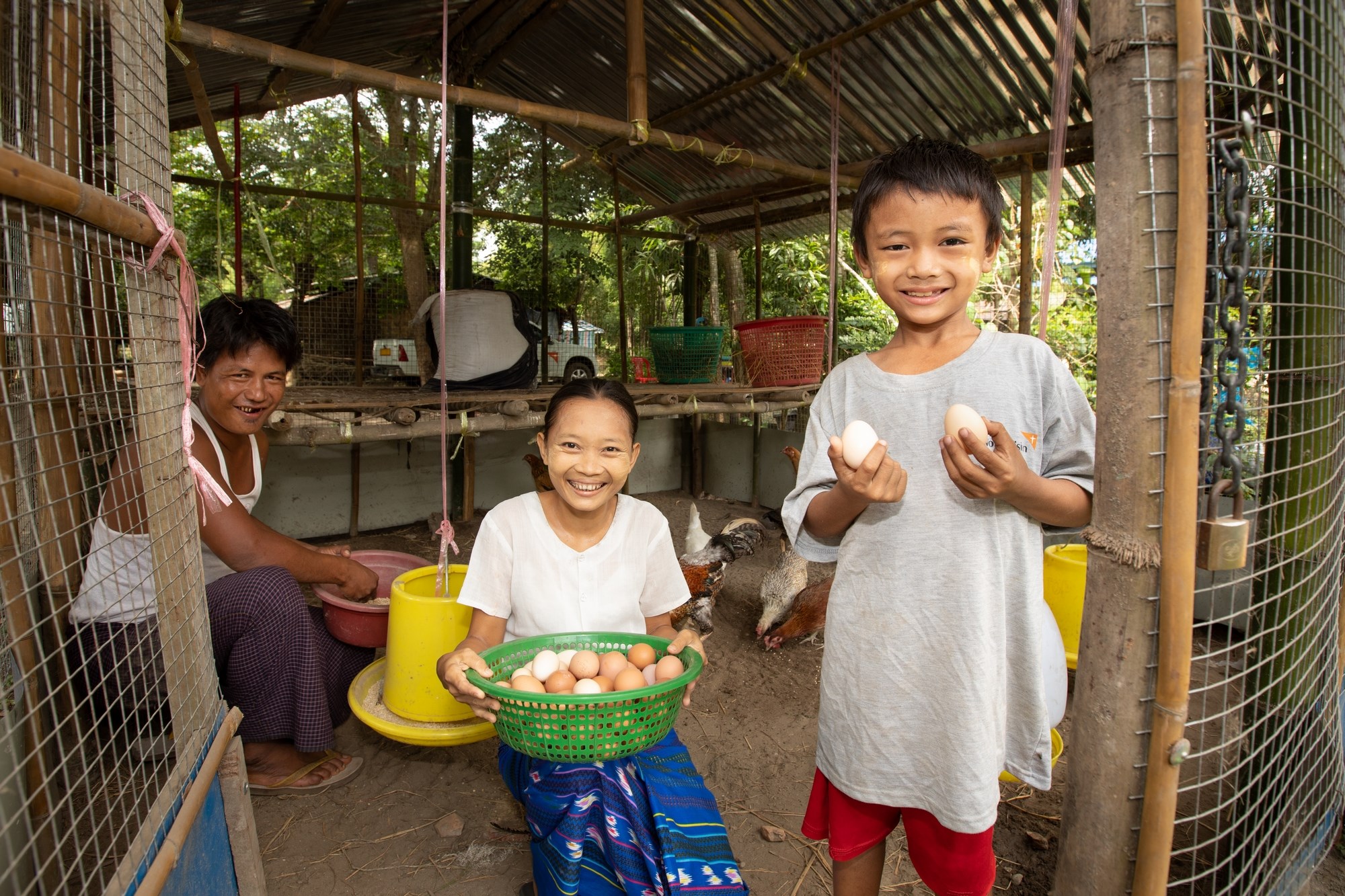 Family in a house in Myanmar, the young boy holding up eggs