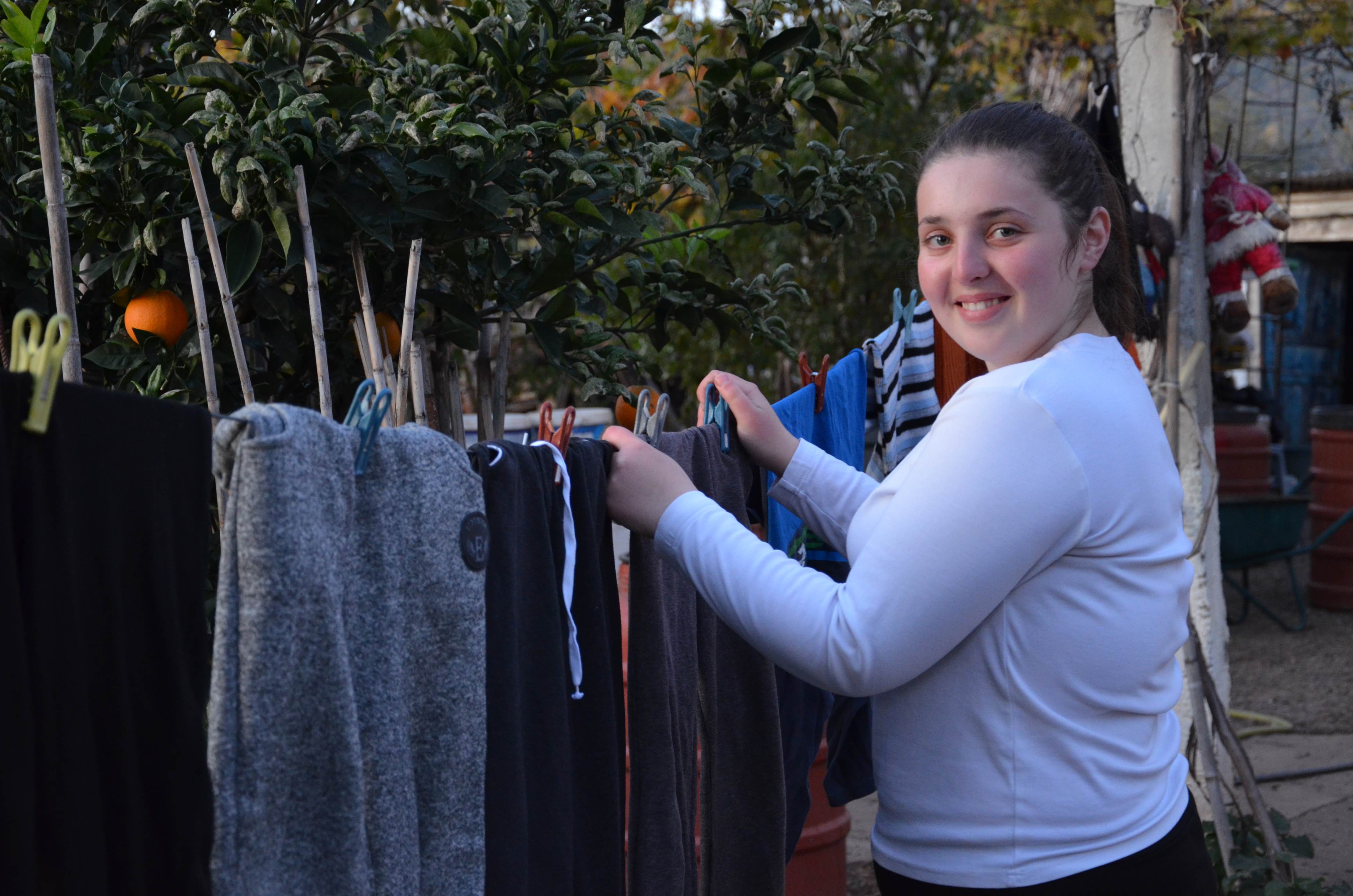 Girl smiles as she stands outside next to a washing line in Albania talking about how sponsorship has impacted her life