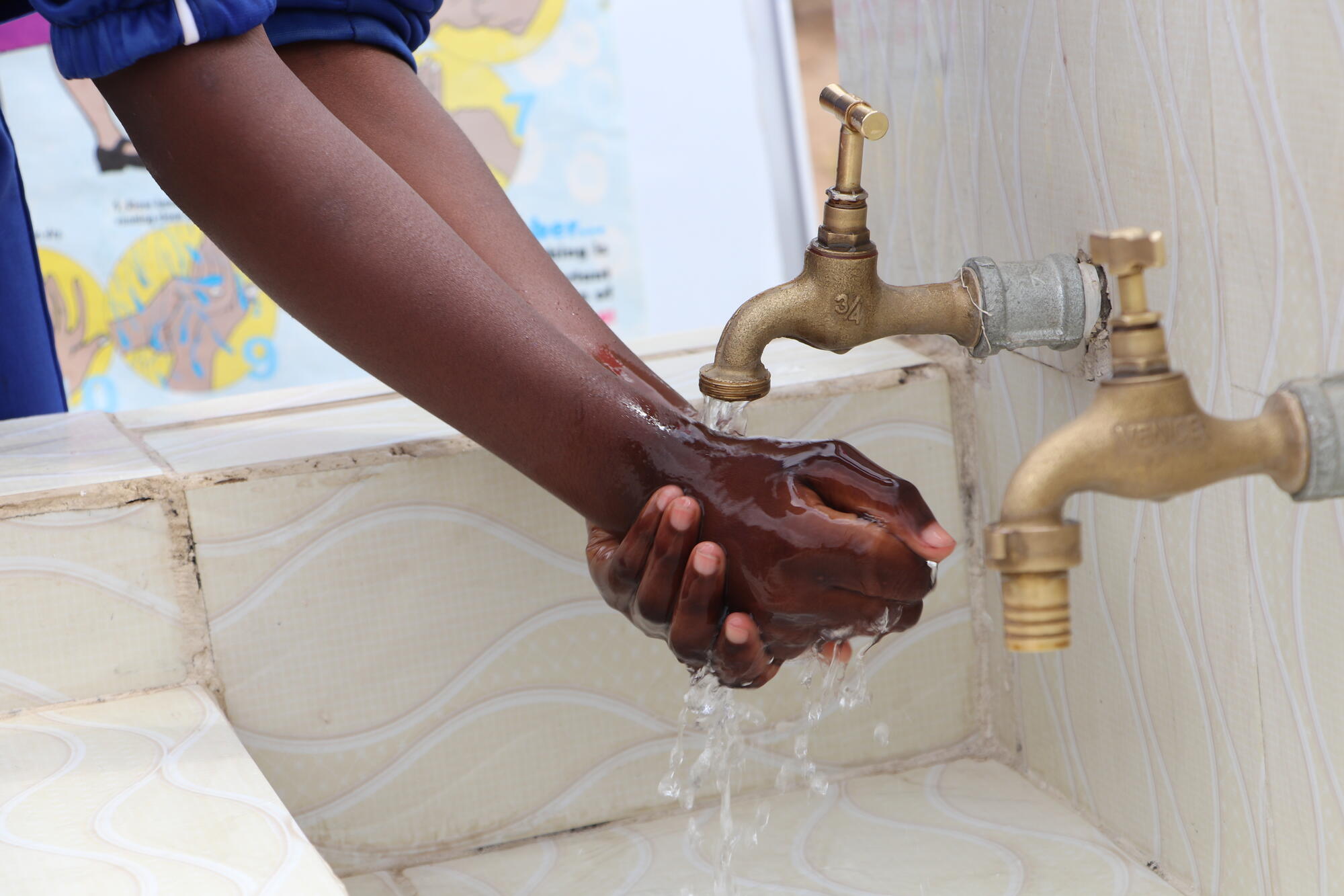 A child washes their hands under two taps