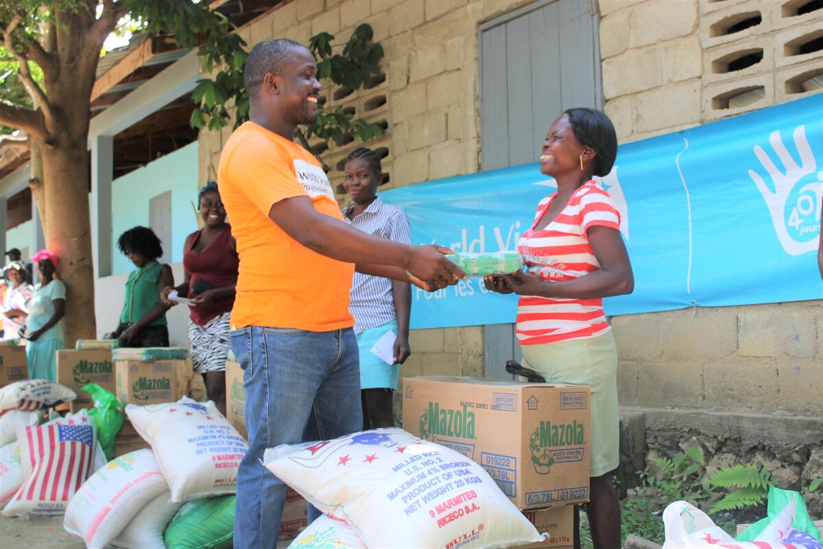 World Vision Haiti staff handing out food packages to Haitian woman