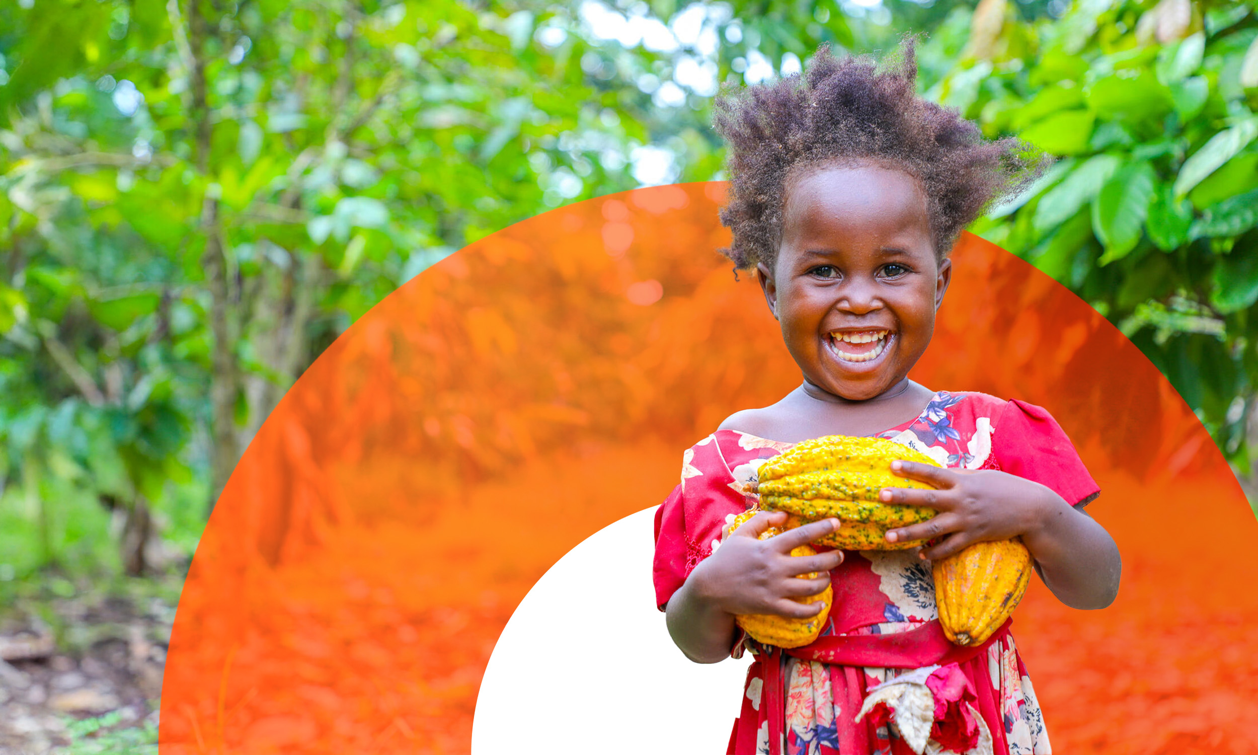 A young girl from Uganda smiles to the camera while carrying vegetables. 