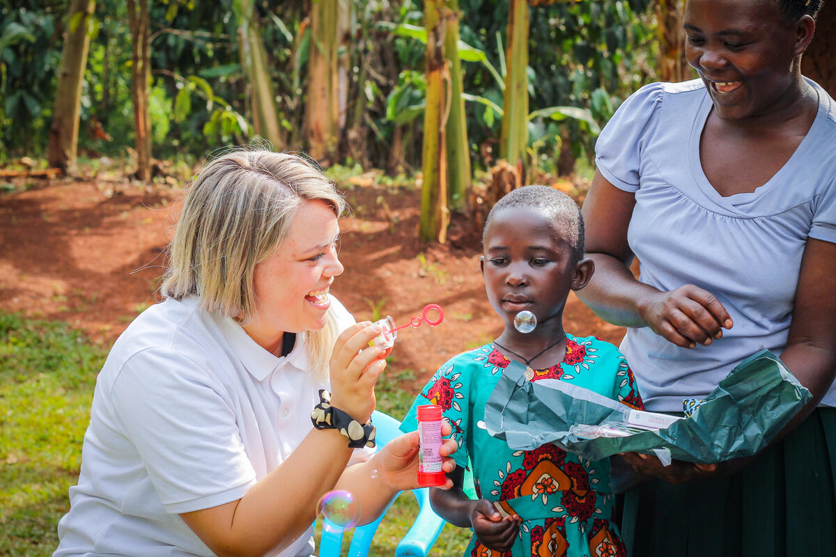 Two women smile as they talk to a sponsored child in Uganda