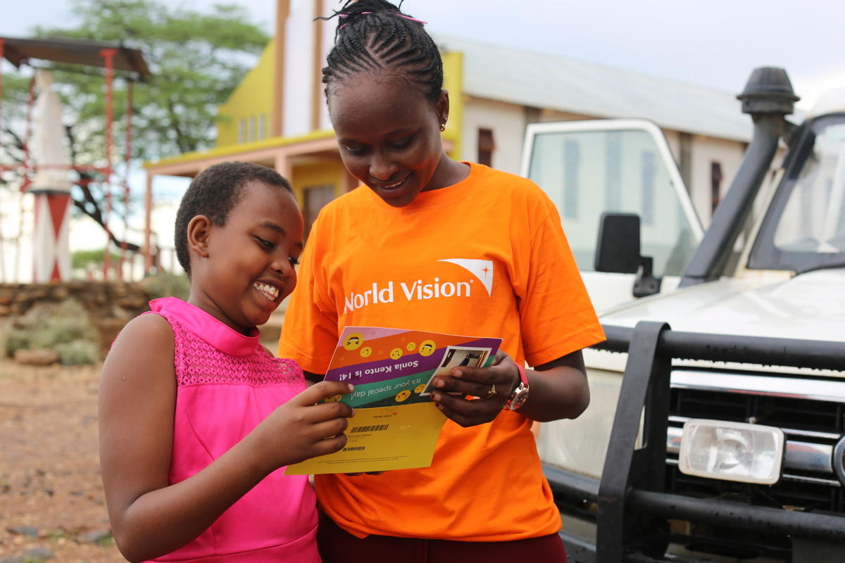 Young sponsored girl in Kenya reads birthday card from sponsor