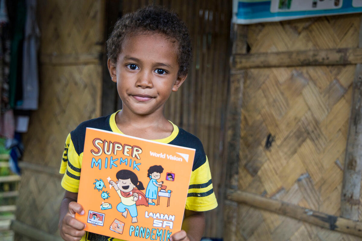 Boy in the Philippines holds storybook about hygiene 