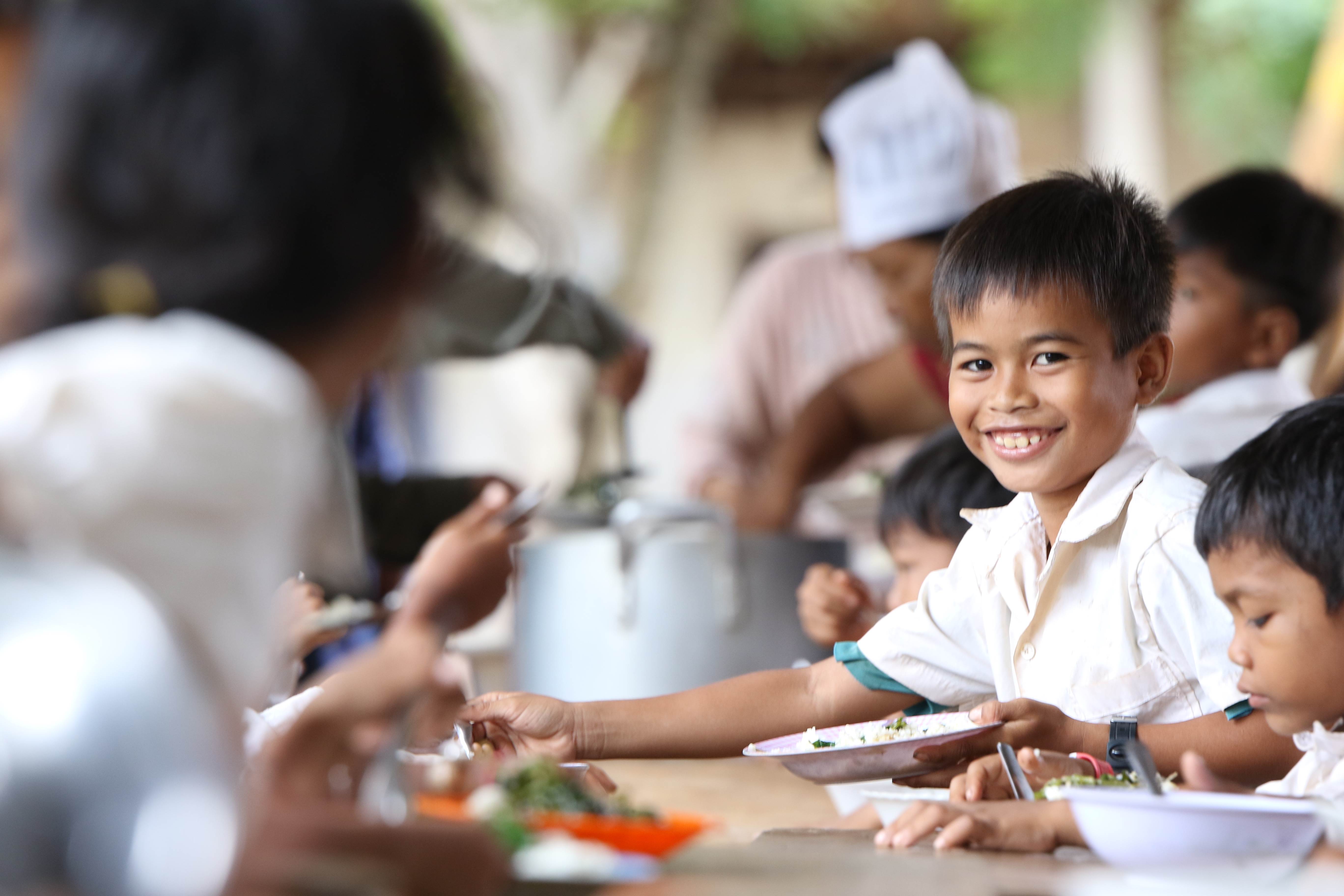 Boy from Cambodia smiling to the camera in a kitchen setting