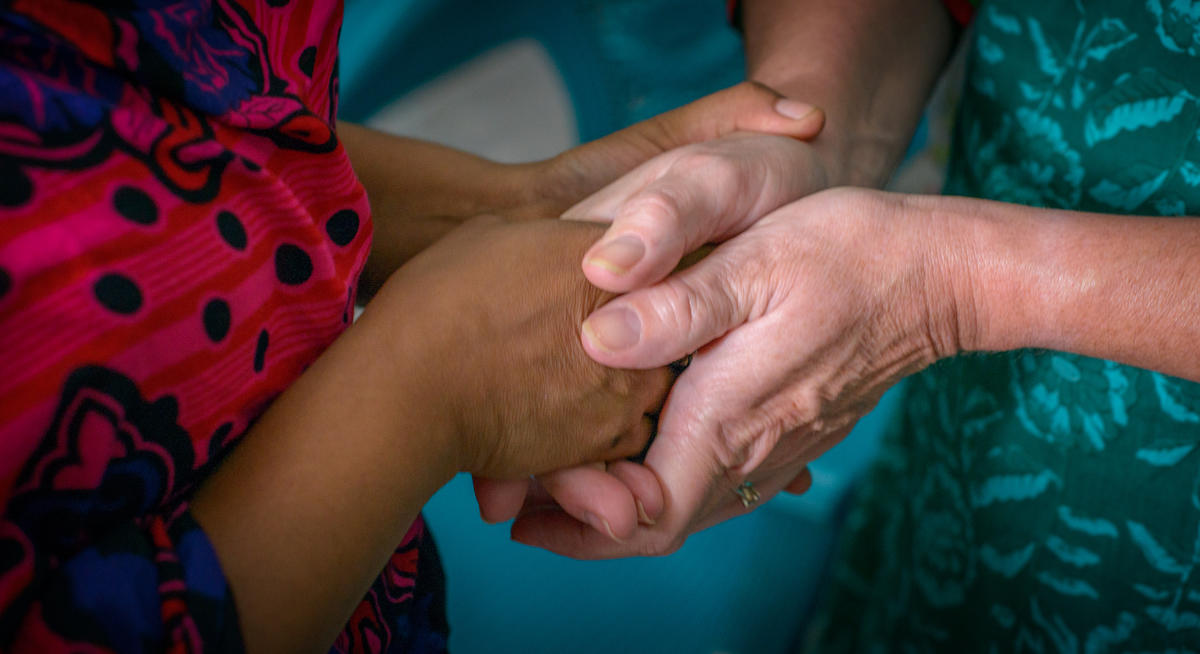 Two pairs of hands clasped in prayer