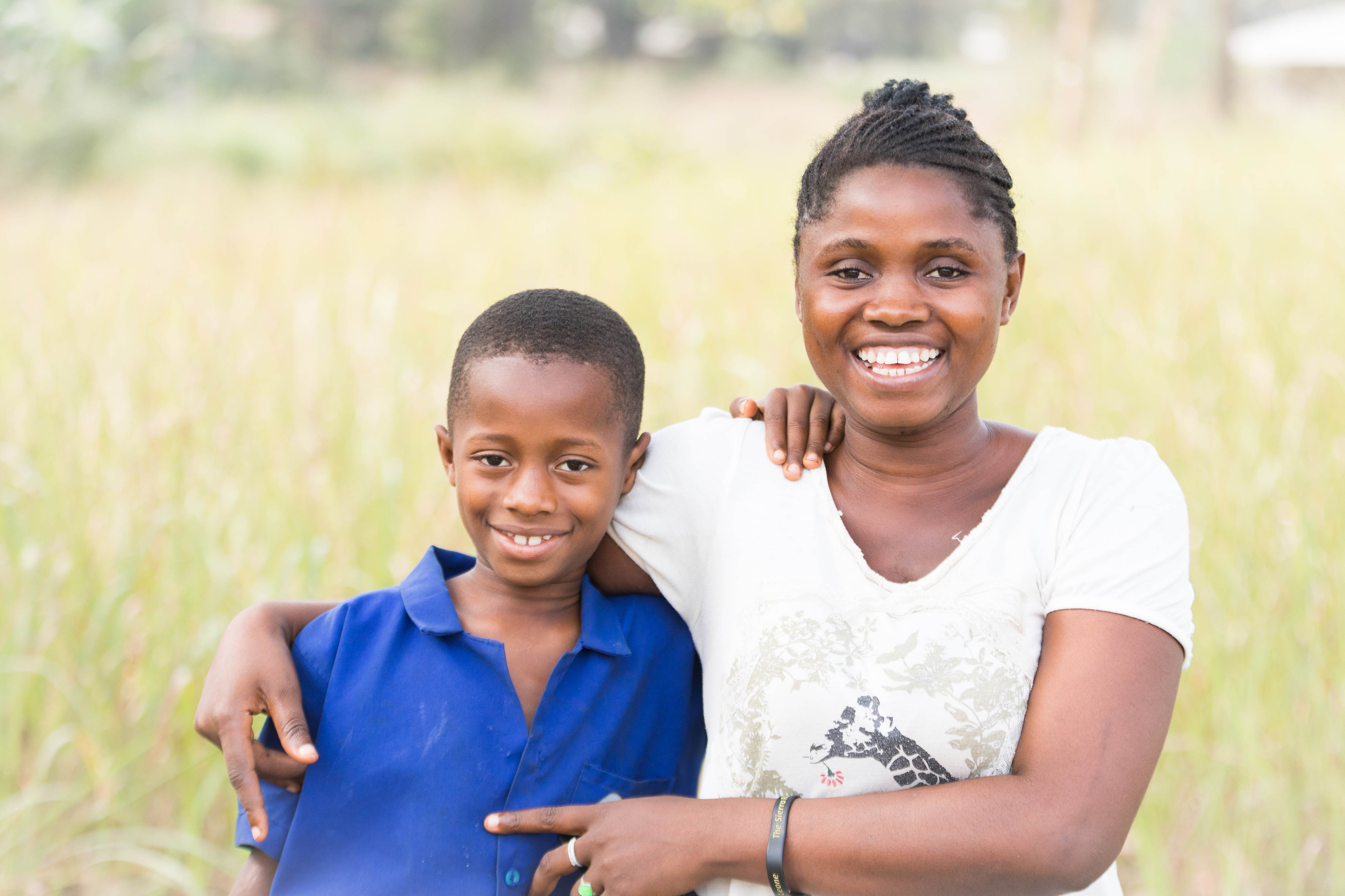 Woman and her son from Sierra Leone smile as they stand in a field