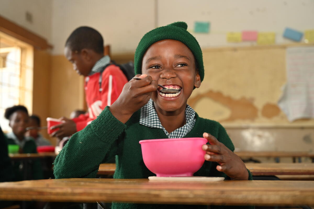 A feeding programme in a school with a child eating at their school desk