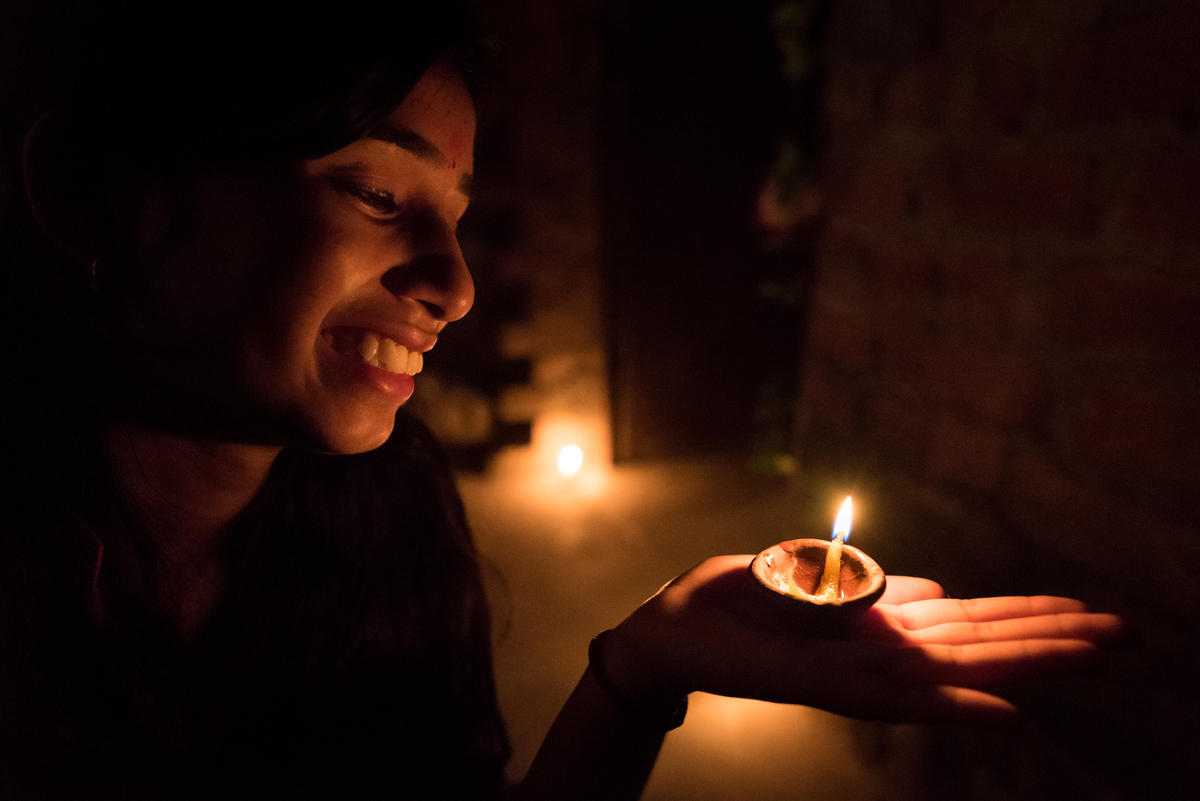 Young girl in India smiles at candle in the dark