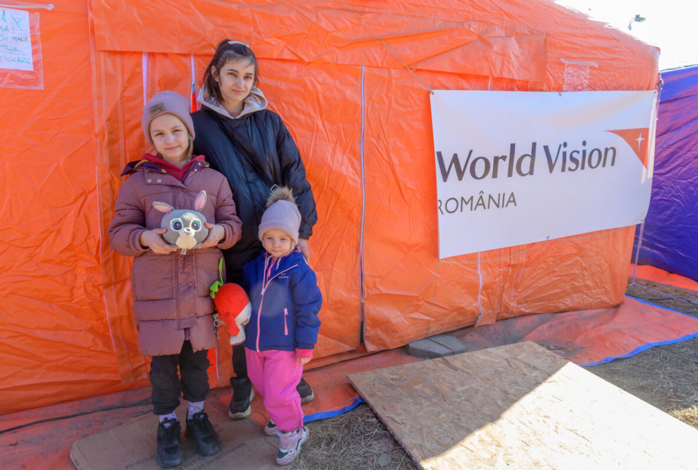 Ukrainian refugee family standing outside World Vision support tent