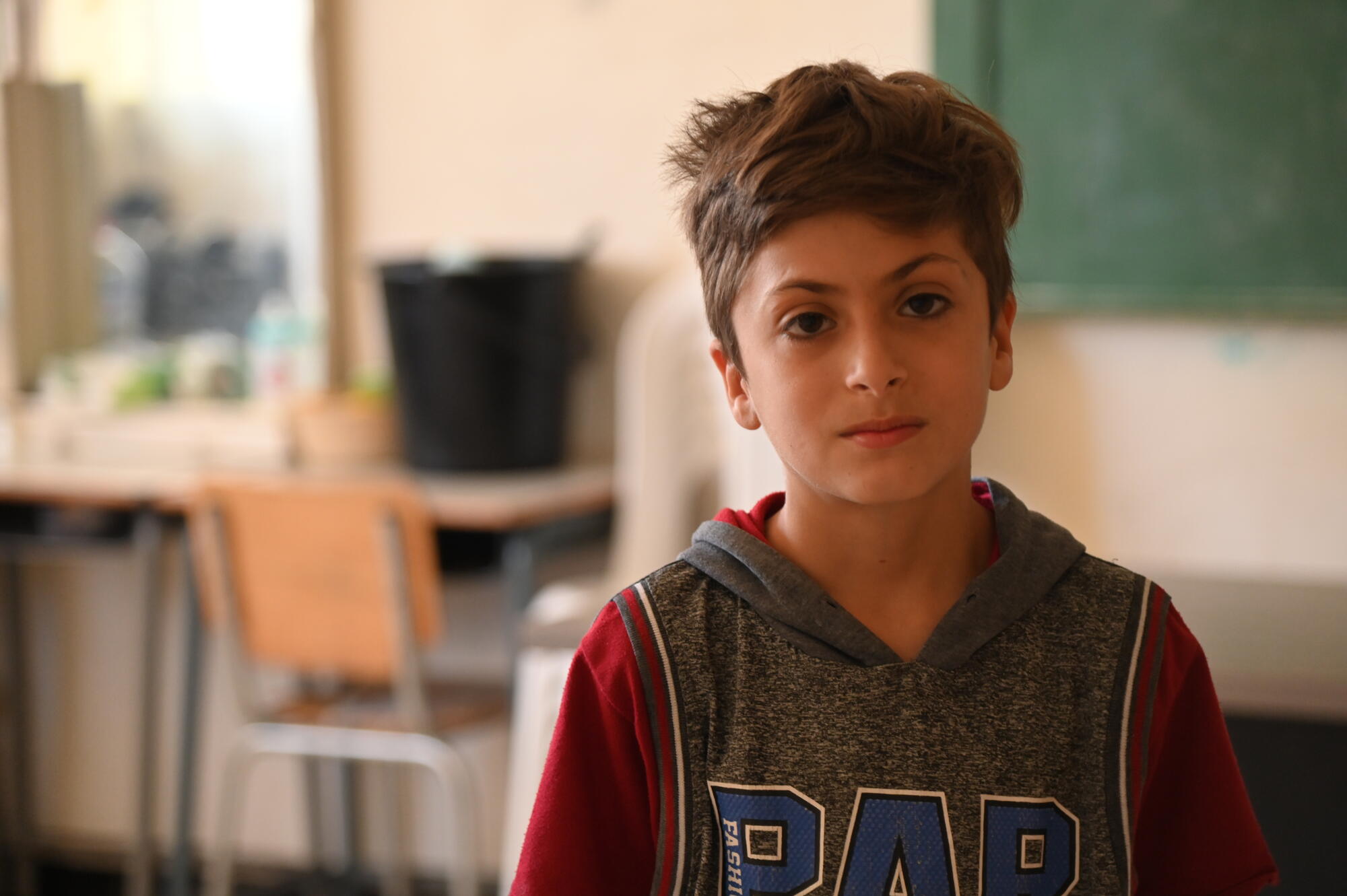 A sad young boy sits alone in a class