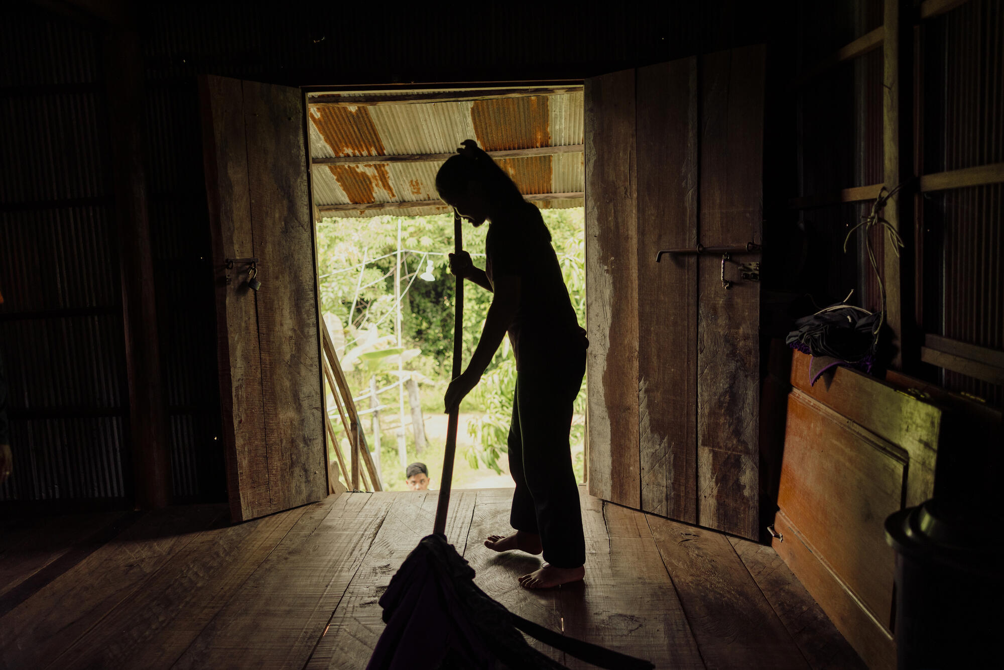 The silhouette of young girl sweeping a house