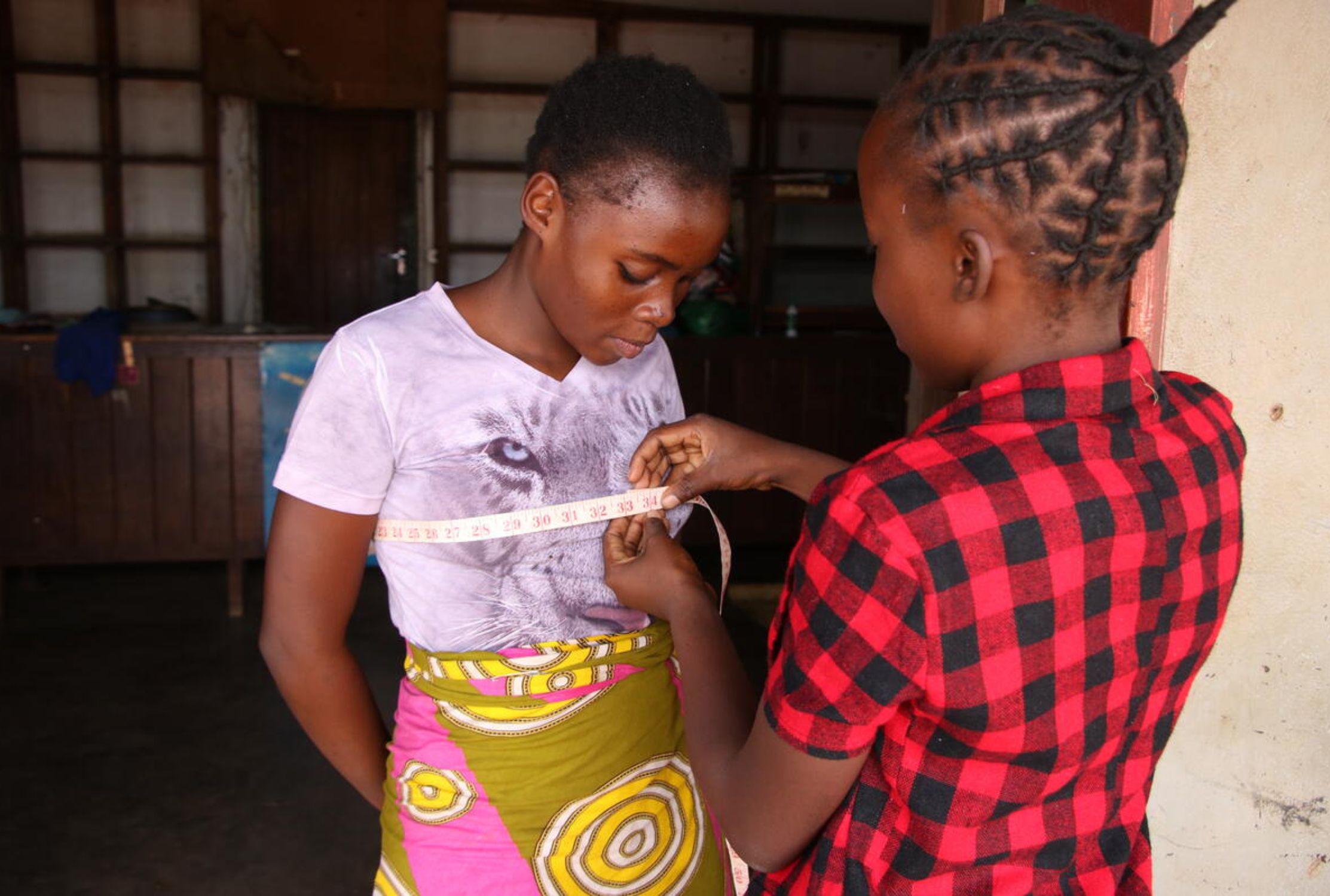 Zambian girl using measuring tap to measure another girl's chest