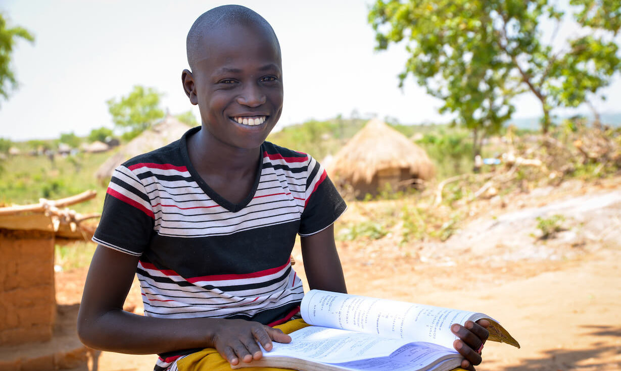 A boy reading a text book outside