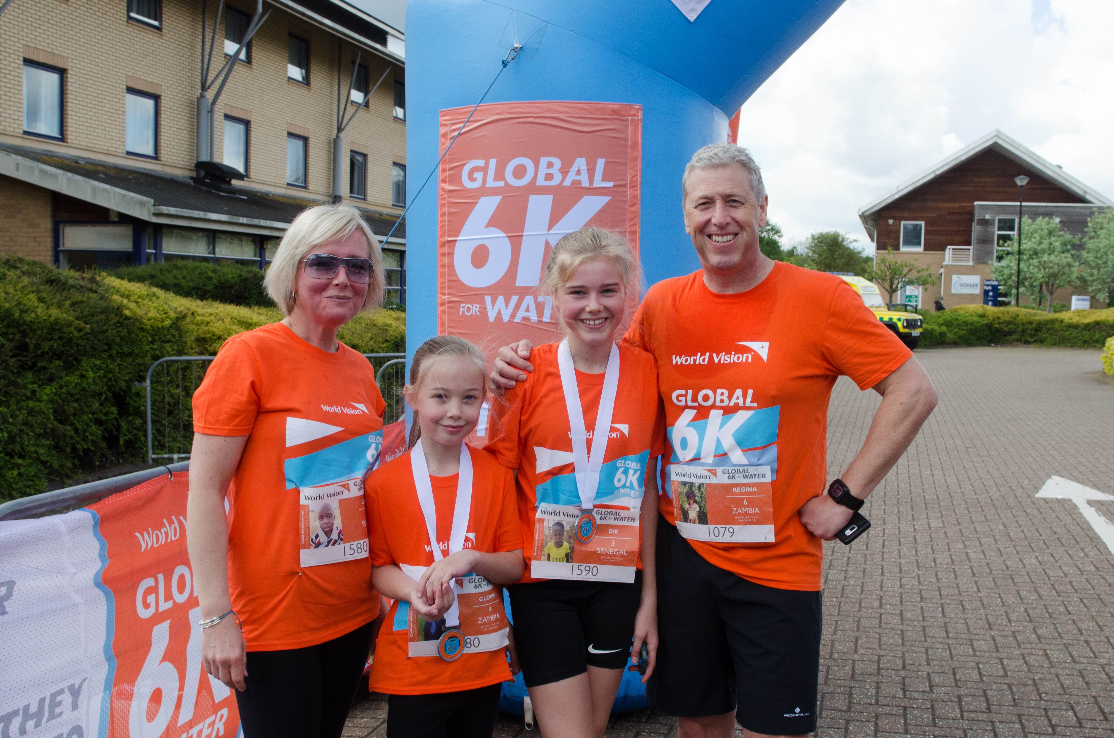 Family in the UK wear World Vision 6K t-shirts and medals, smiling