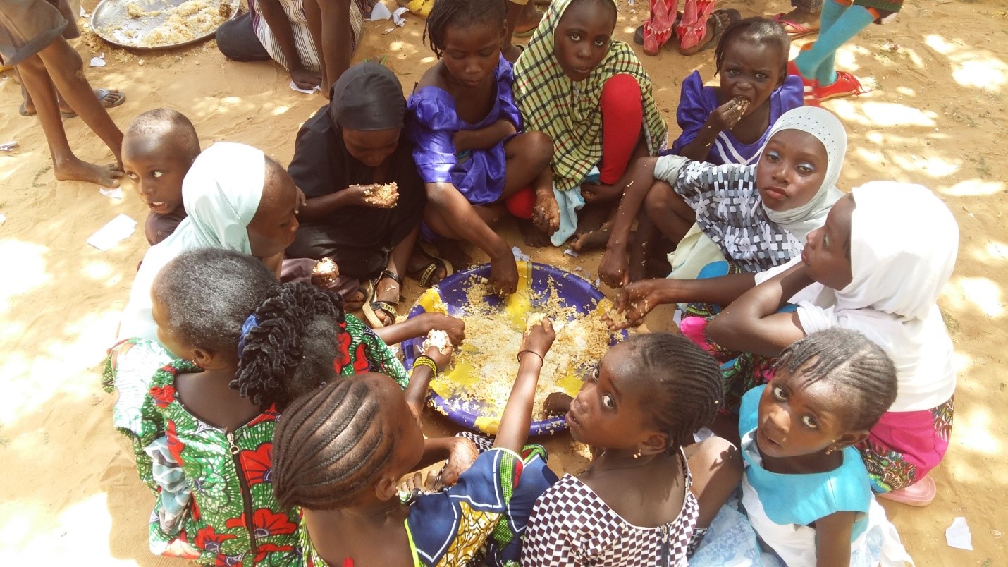 Group of people in Niger sit in a circle around a shared pot of food