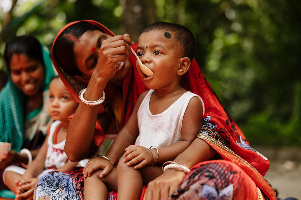 A mother feeding her young child food, Bangladesh