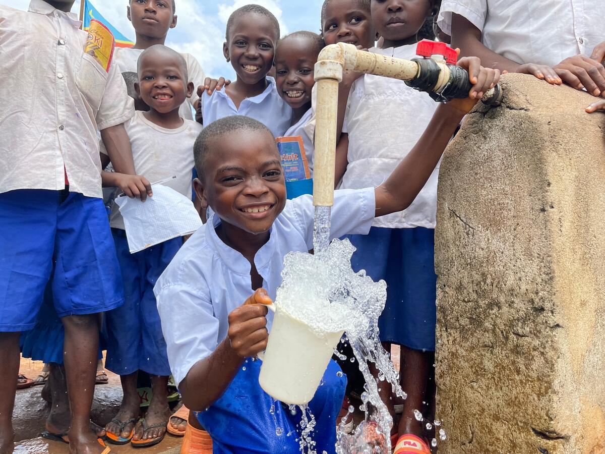 Children in DRC collect water from a newly installed water point