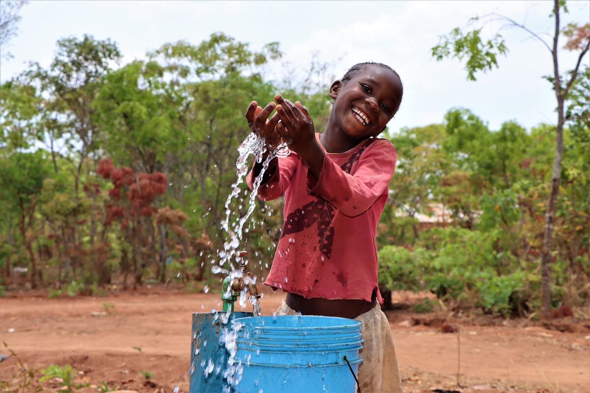 Mercy, in Malawi, splashing clean water from a bucket
