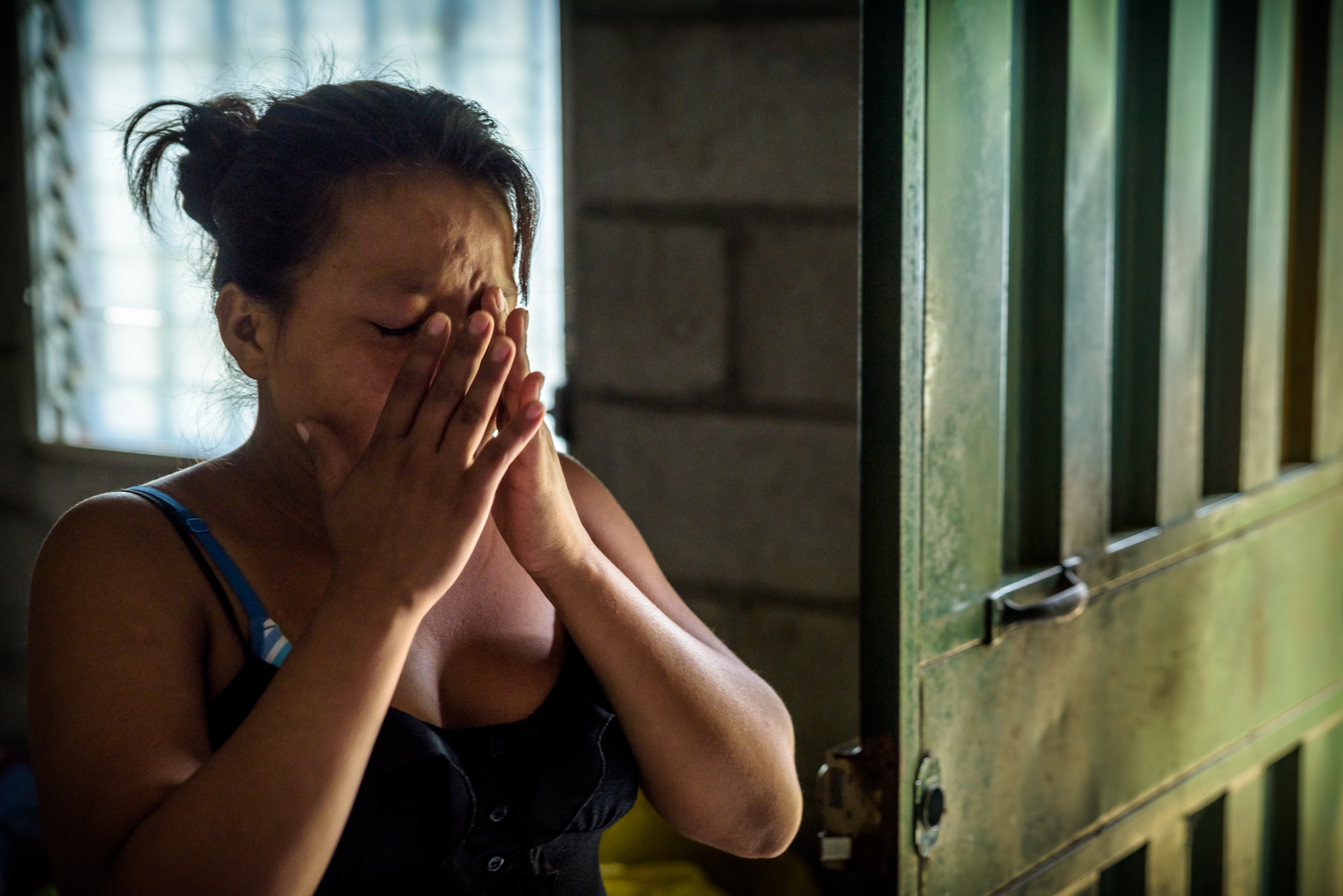 Woman in Honduras clasps her hands to her face as she tears up