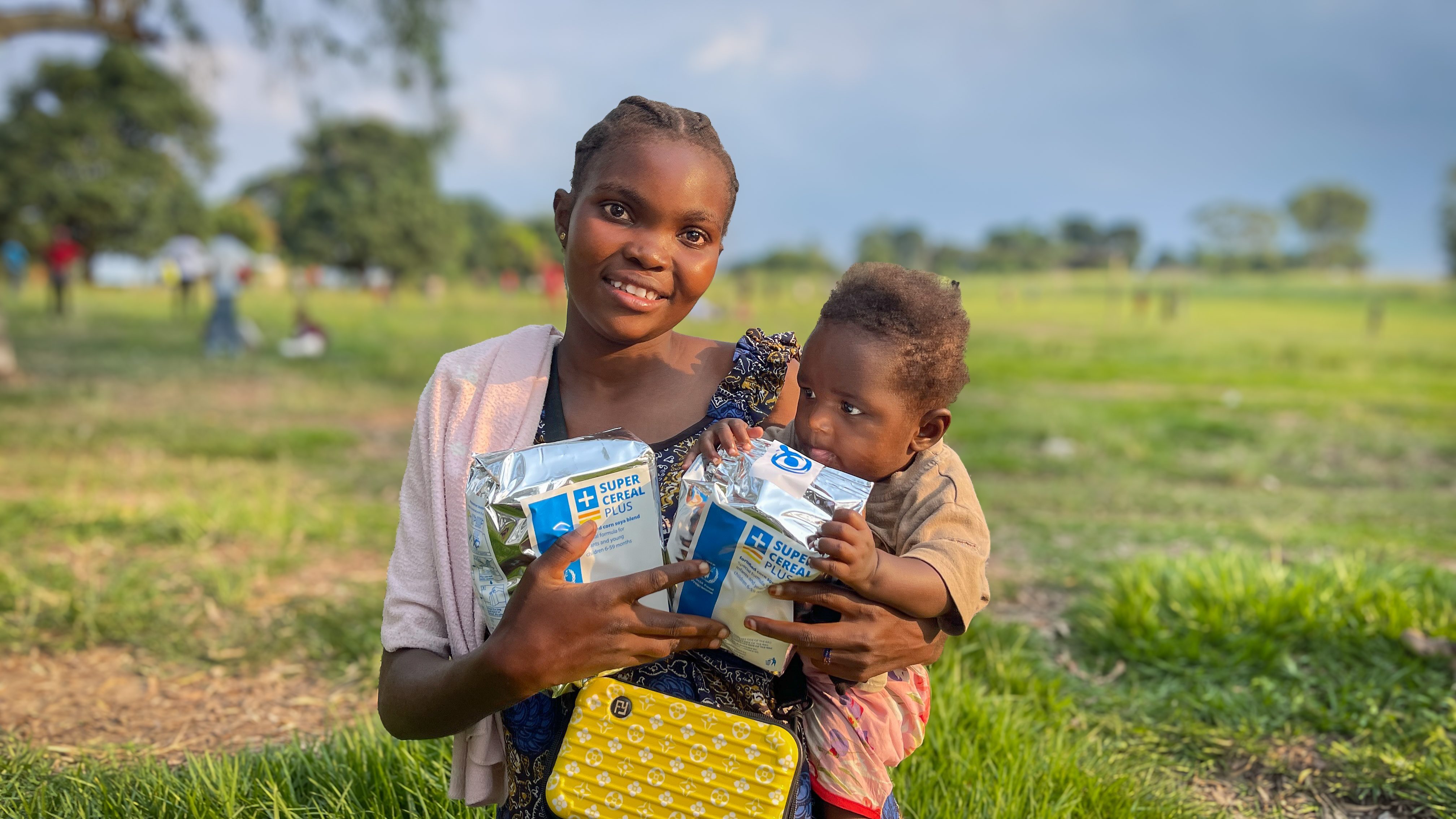Mother smiling and carrying her young son in DRC having received emergency food supplies