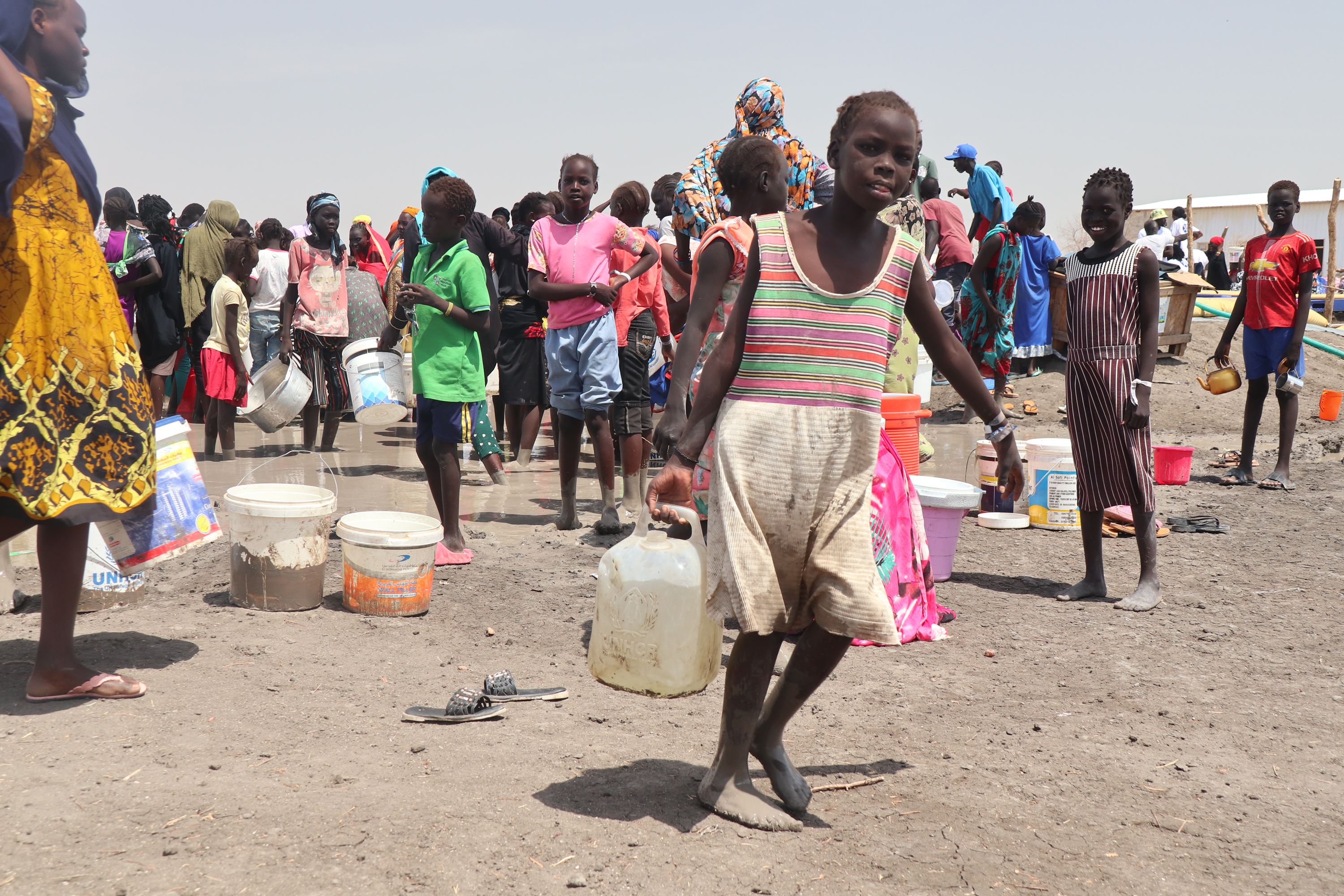 A child carries a large bottle of water