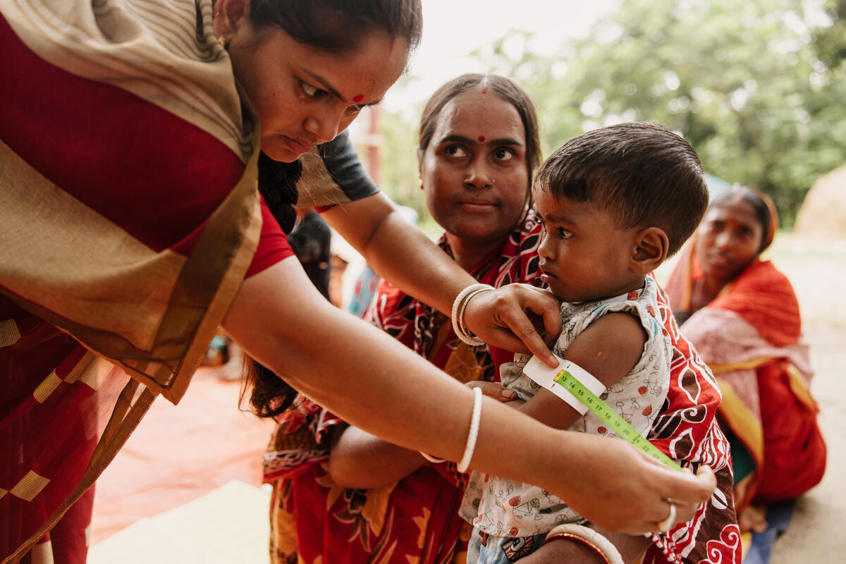 A child in Bangladesh has their arm measured in a health clinic