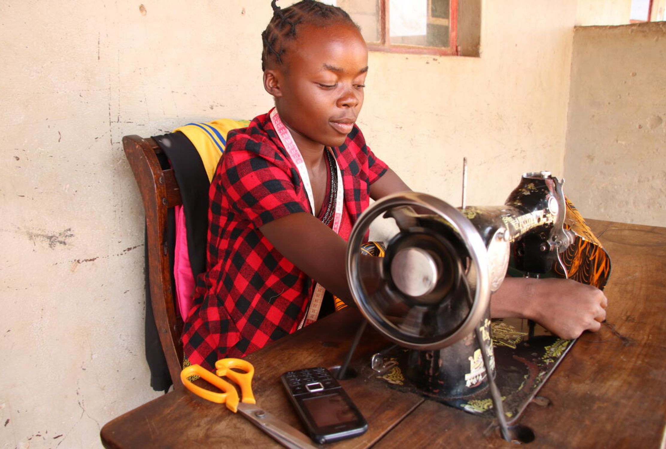 Ugandan girl smiles while using a sewing machine