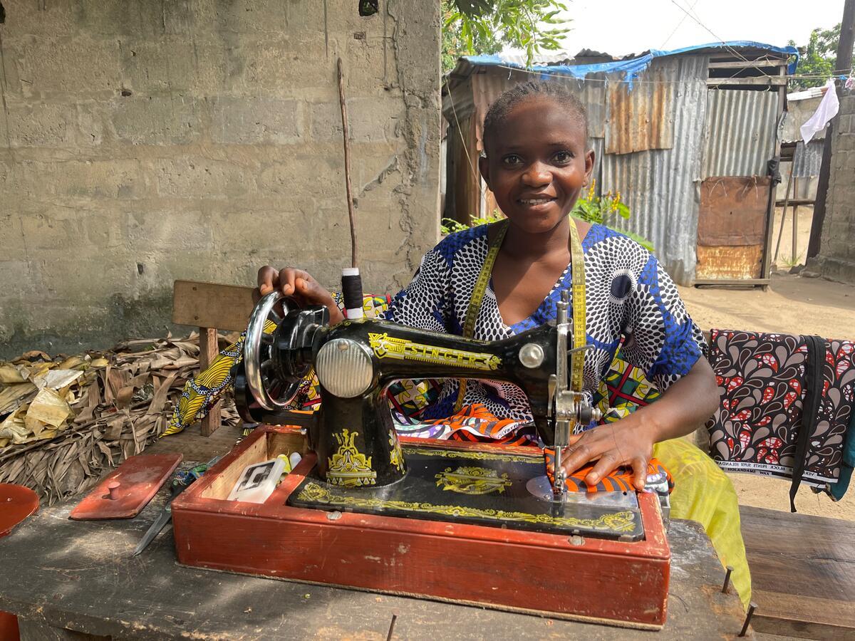 A young woman sits a a sewing machine, DRC