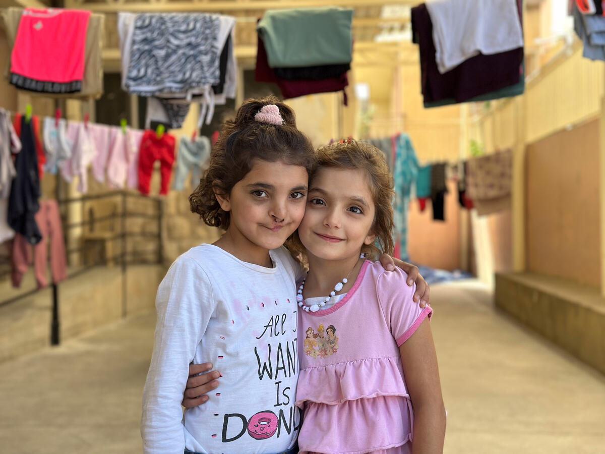 Two young girls standing together in a residential courtyard.