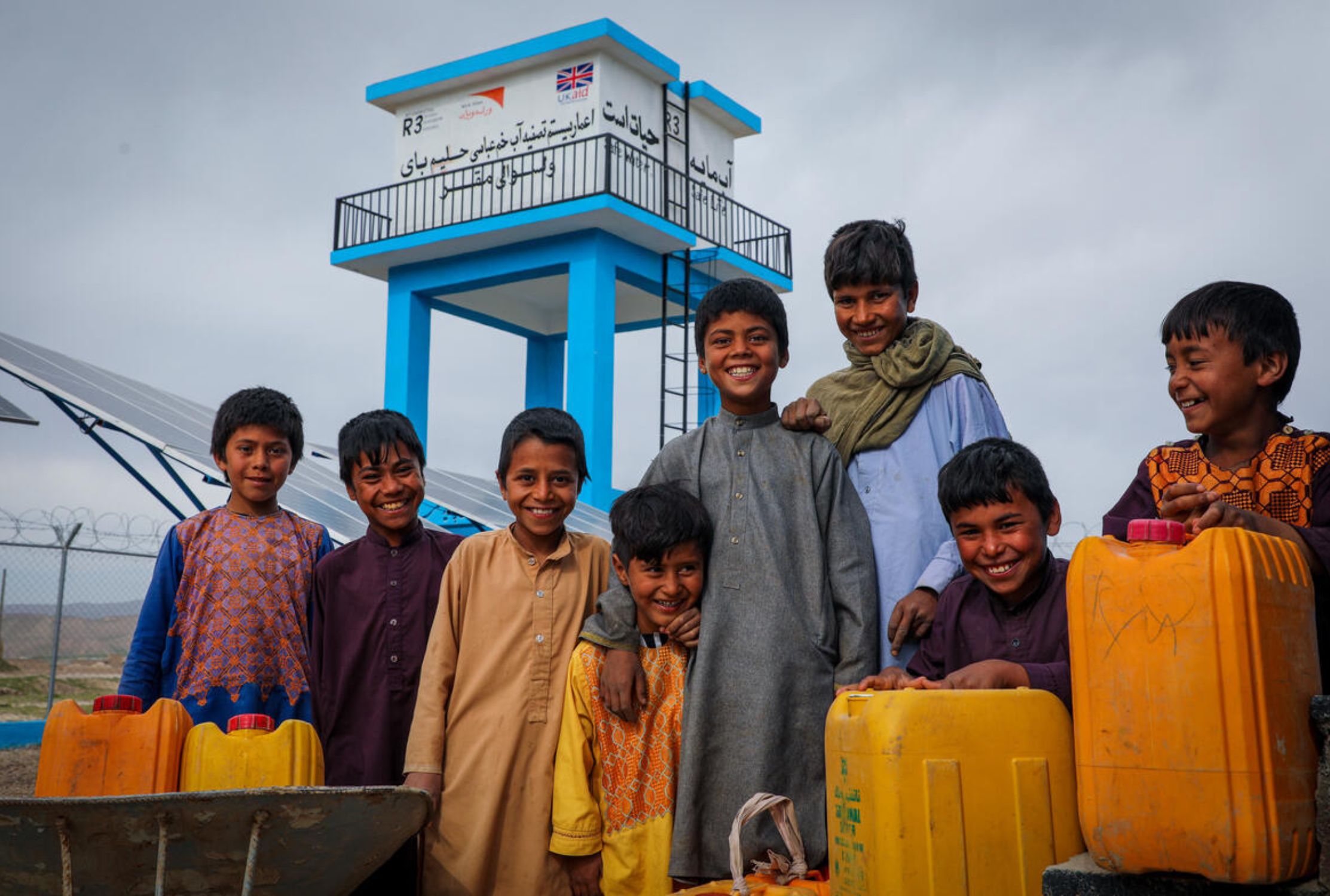 Children in Afghanistan smile together as they hold hygiene kits provided for COVID-19 protection