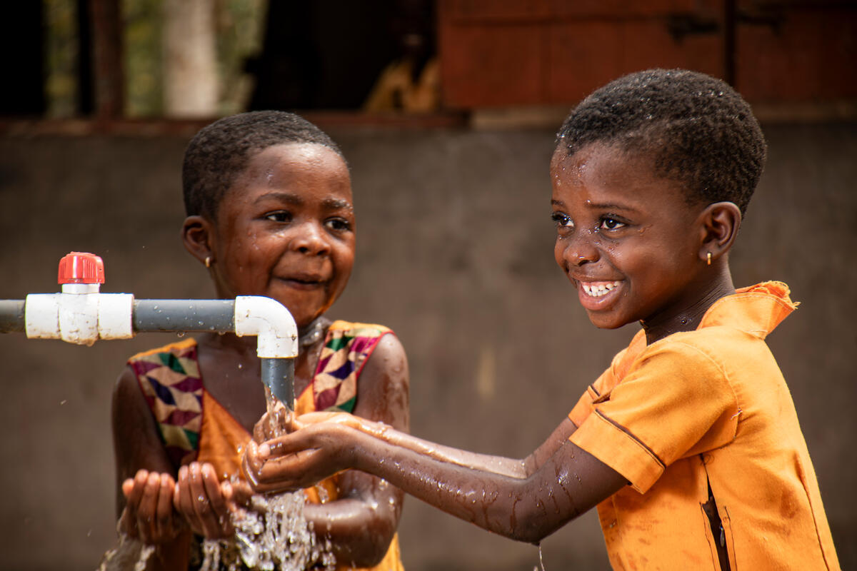 Two children using a water pump in Ghana