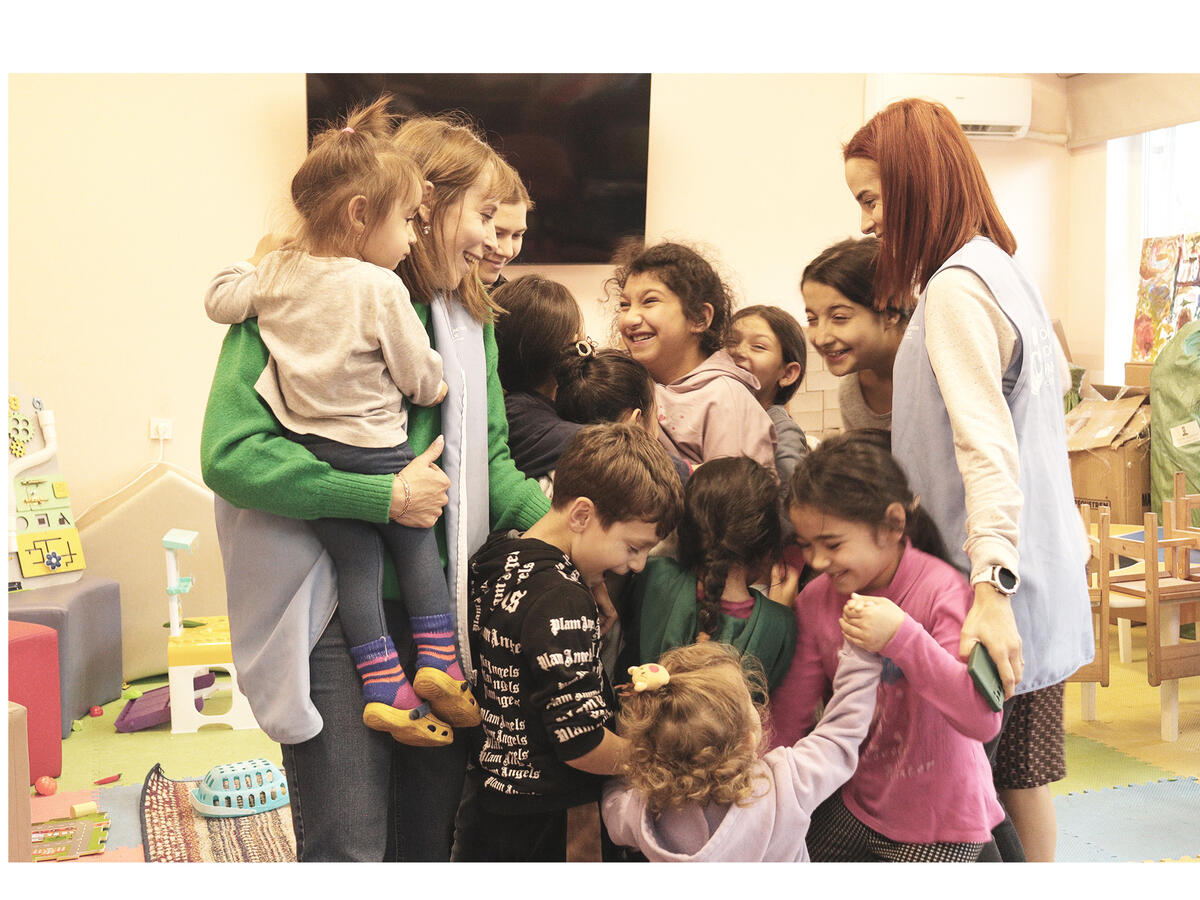 Large group of Ukrainian refugee children smiling and laughing with three adults