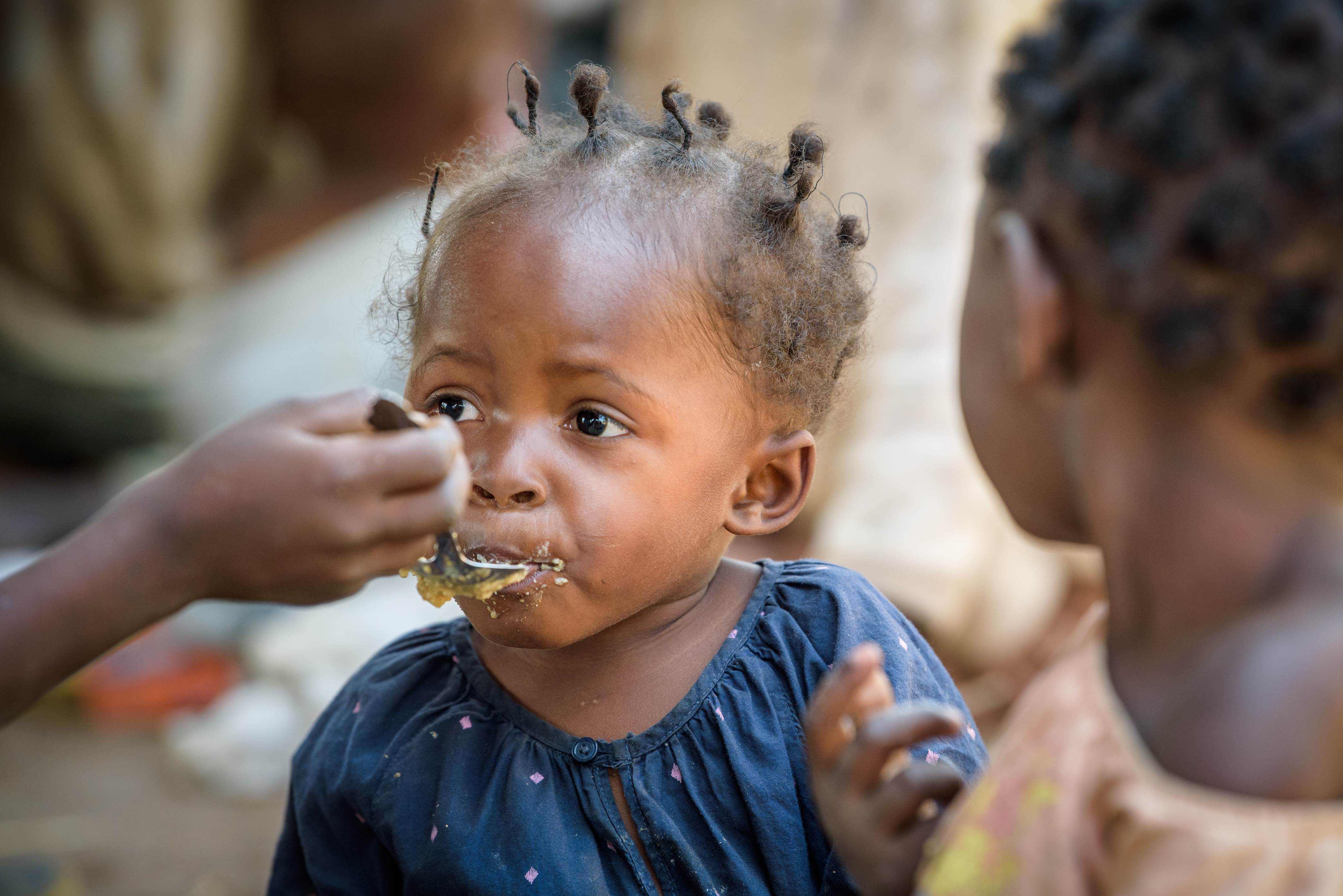 A young girl from the DRC being fed with a spoon