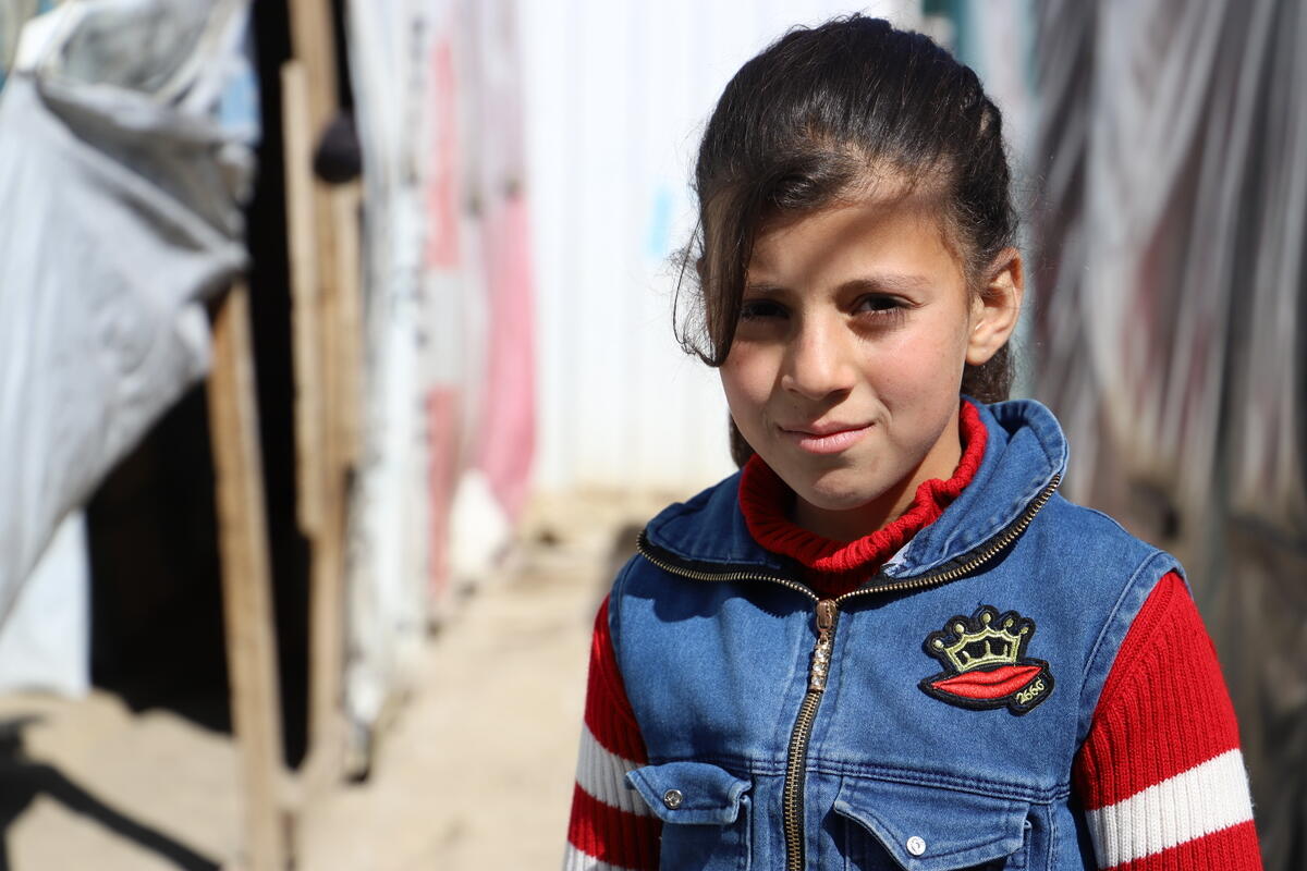 A Syrian girl sits outside tents in a settlement camp for refugees in Lebanon