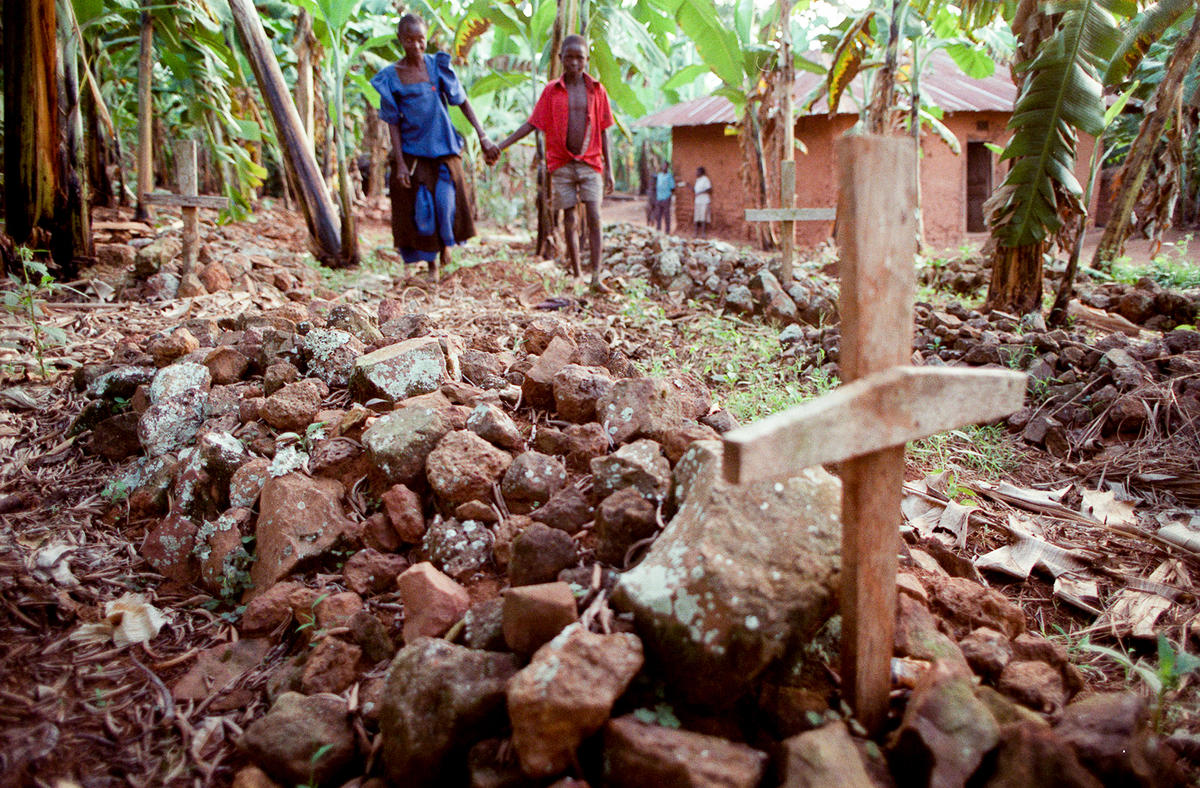 People walk around graves near their house