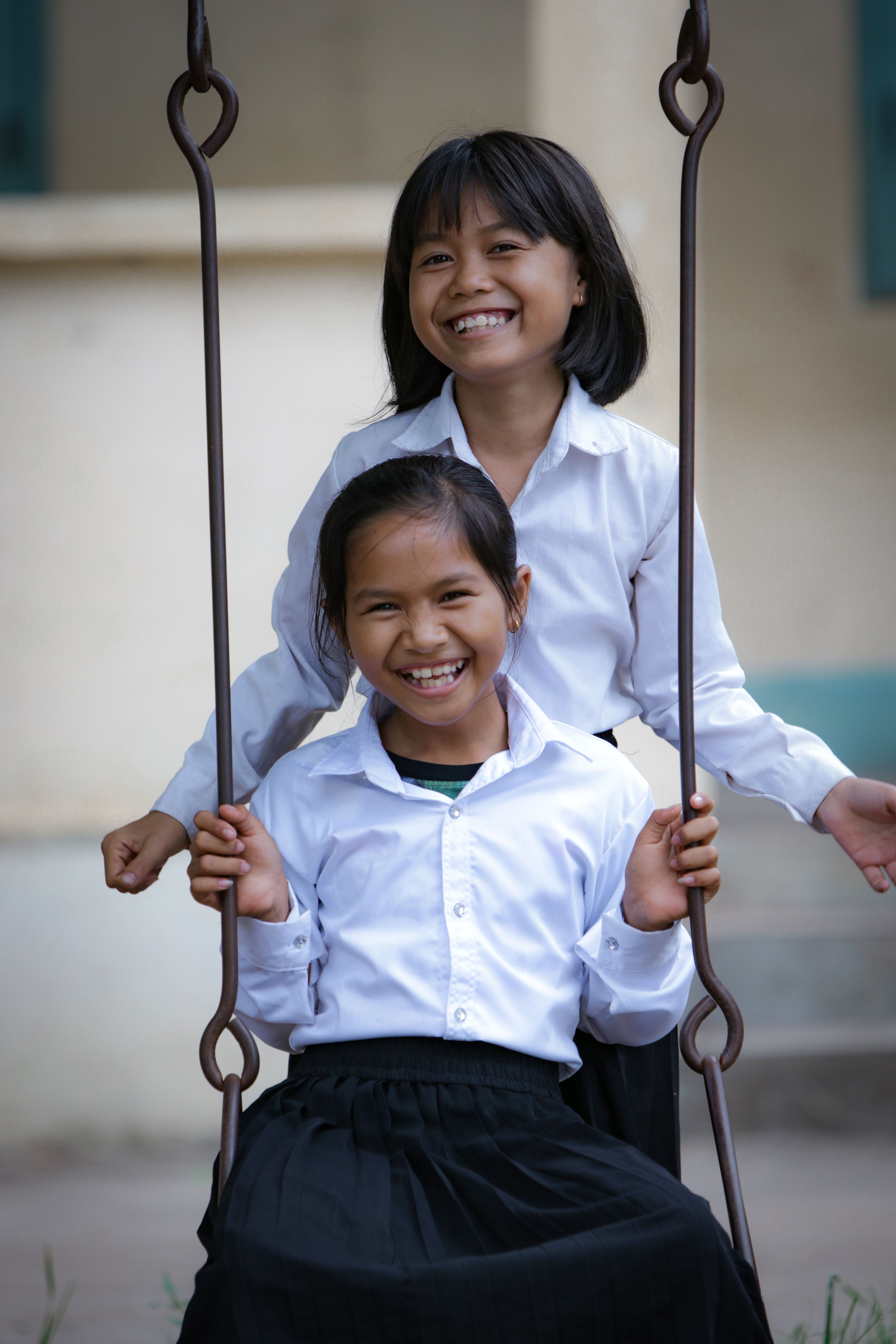 Child smiles as they play with a toy, surrounded by other children sitting on the floor in a Child Friendly Space in DRC