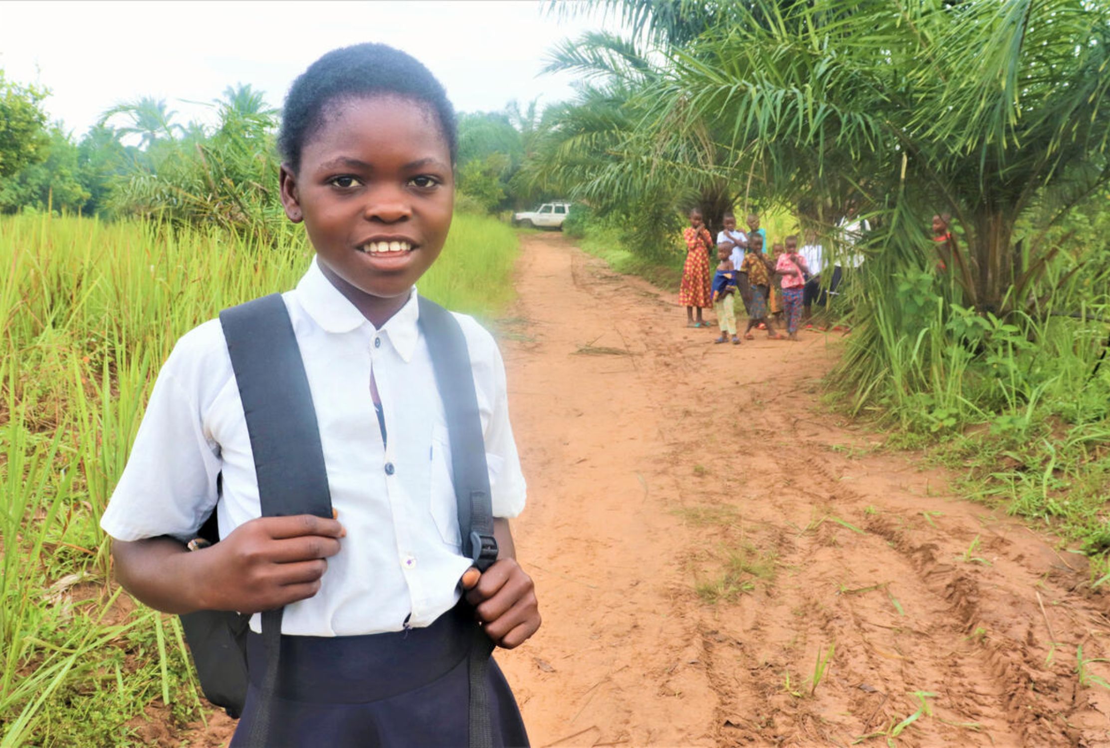 Girl from DRC on her way to school wearing the uniform and a backpack 