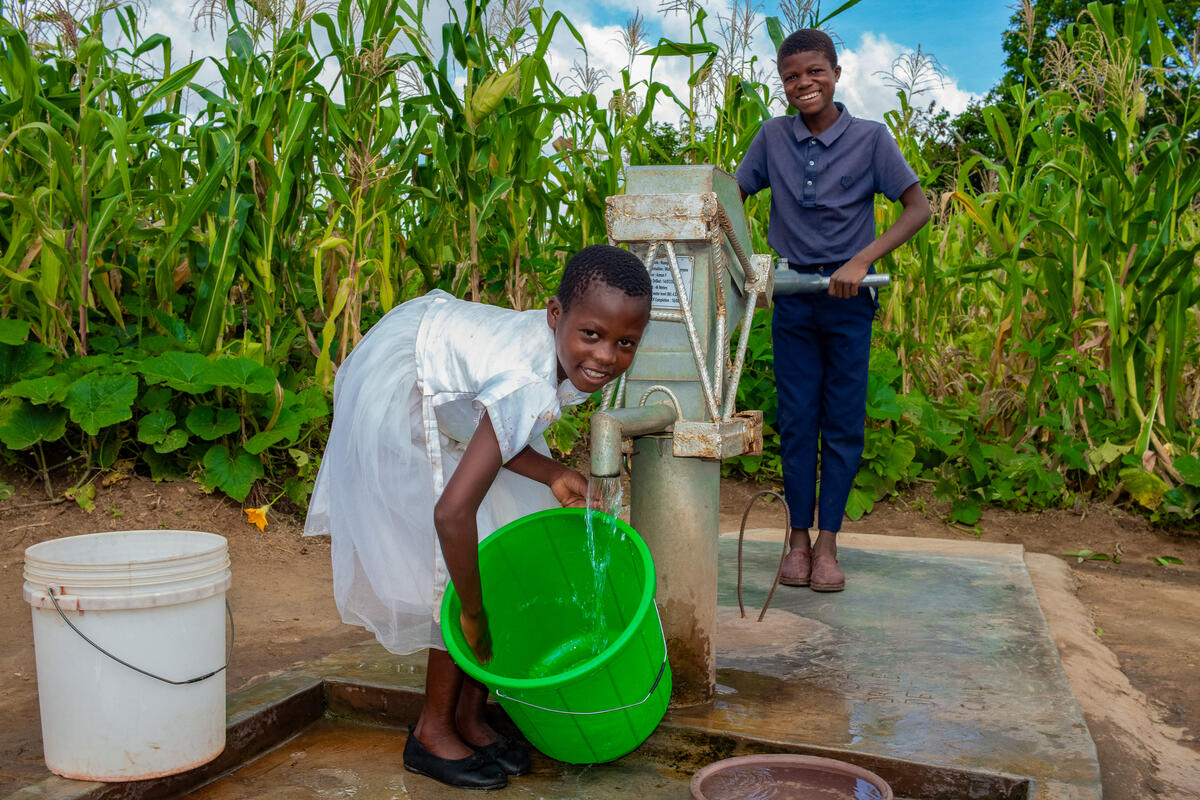 Boy and girl collecting a bucket of water from a borehole in Malawi